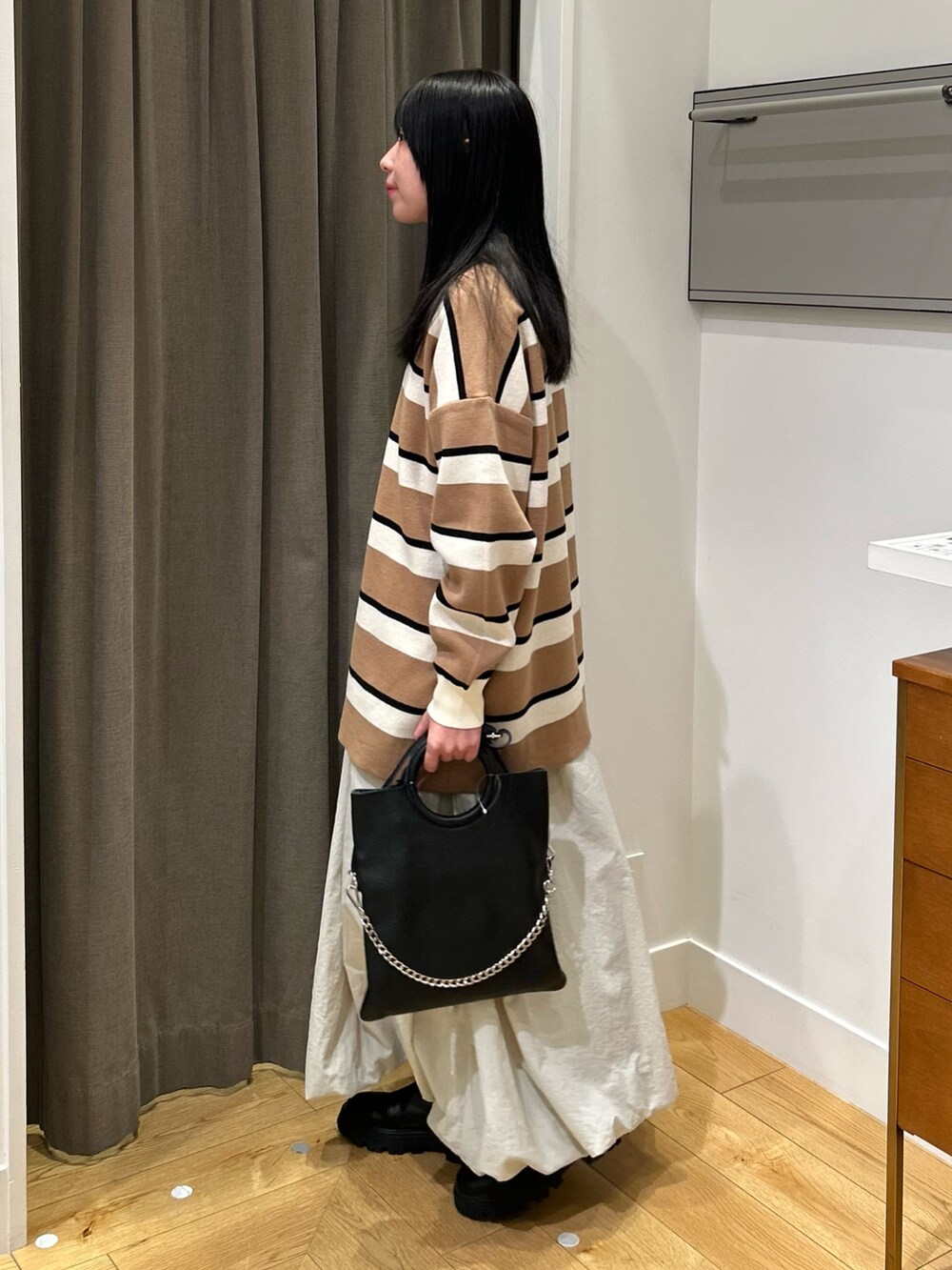 ホワイト系のスカート、ブラック系のブーツ、ベージュ系のニット/セーターを着用したレディースの秋コーディネートの2枚目の写真