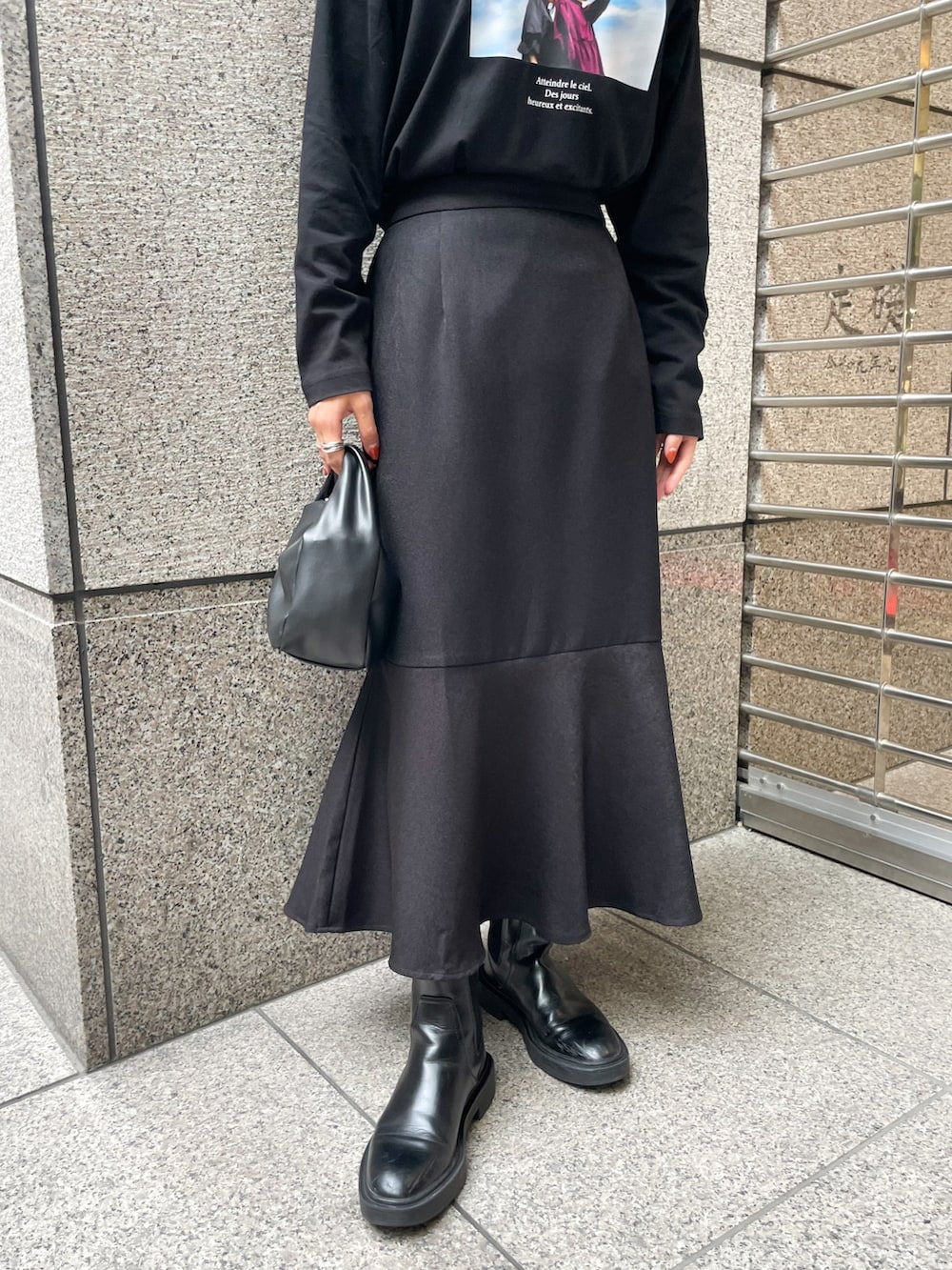 ブラック系のスカート、ブラック系のTシャツ/カットソー、ブラック系のショルダーバッグを着用したレディースの秋コーディネートの5枚目の写真