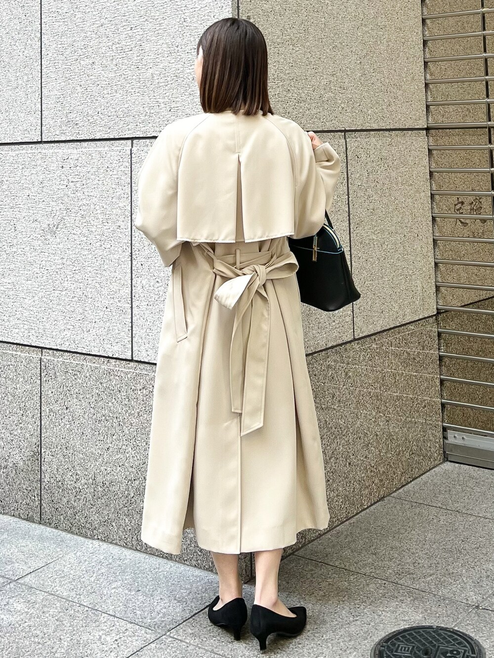 ブルー系のワンピース、ベージュ系のトレンチコート、ブラック系のショルダーバッグを着用したレディースの春コーディネートの2枚目の写真