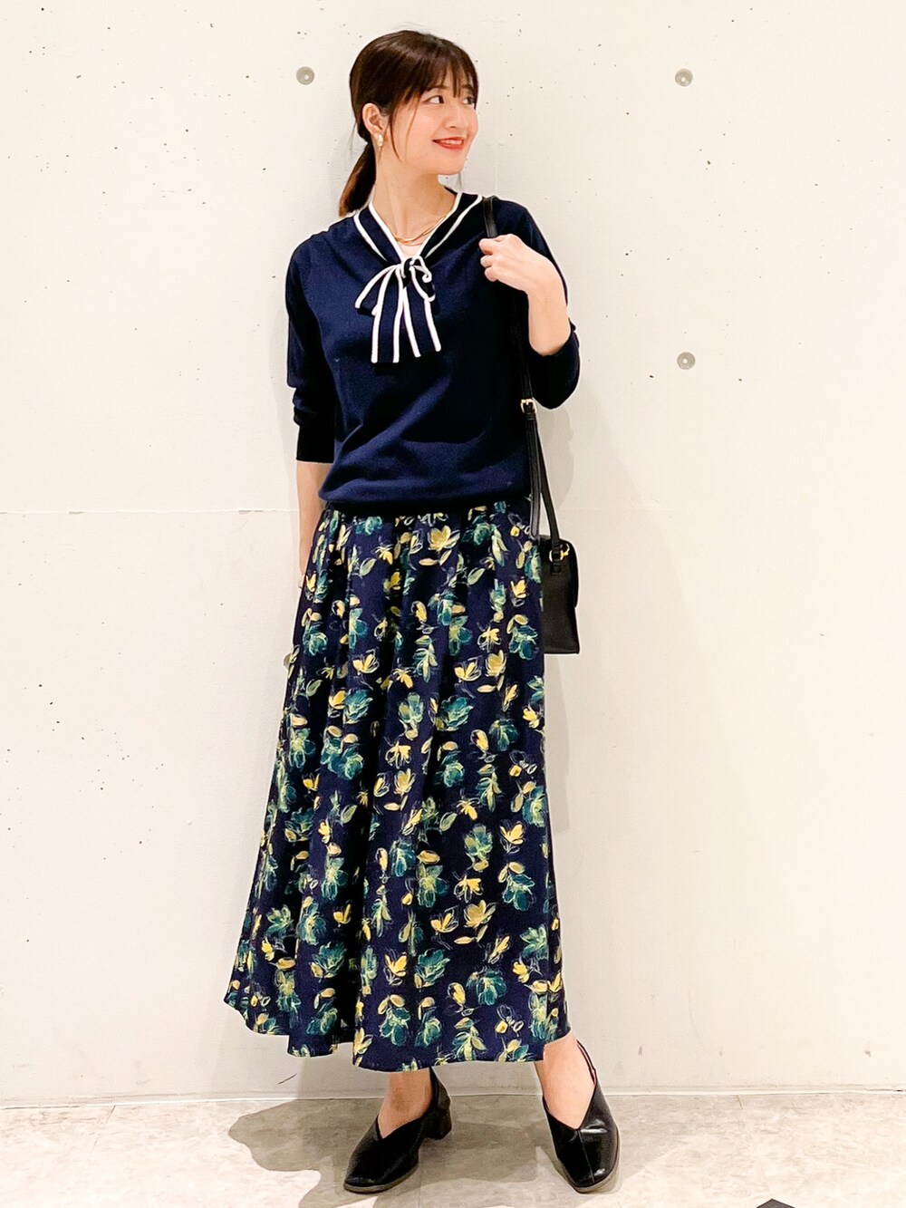 ブルー系のカーディガン/ボレロ、ブルー系のスカート、ブラック系のショルダーバッグを着用したレディースの春コーディネートの2枚目の写真