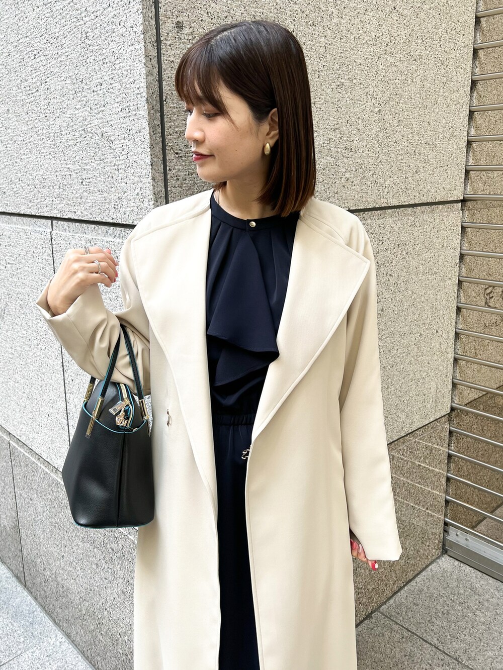 ブルー系のワンピース、ベージュ系のトレンチコート、ブラック系のショルダーバッグを着用したレディースの春コーディネートの3枚目の写真