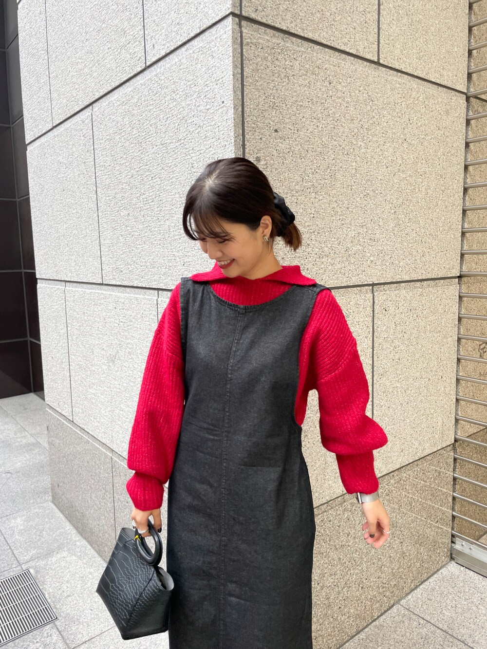 ピンク系のニット/セーター、ブラック系のジャンパースカート、ブラック系のブーツを着用したレディースの冬コーディネートの3枚目の写真