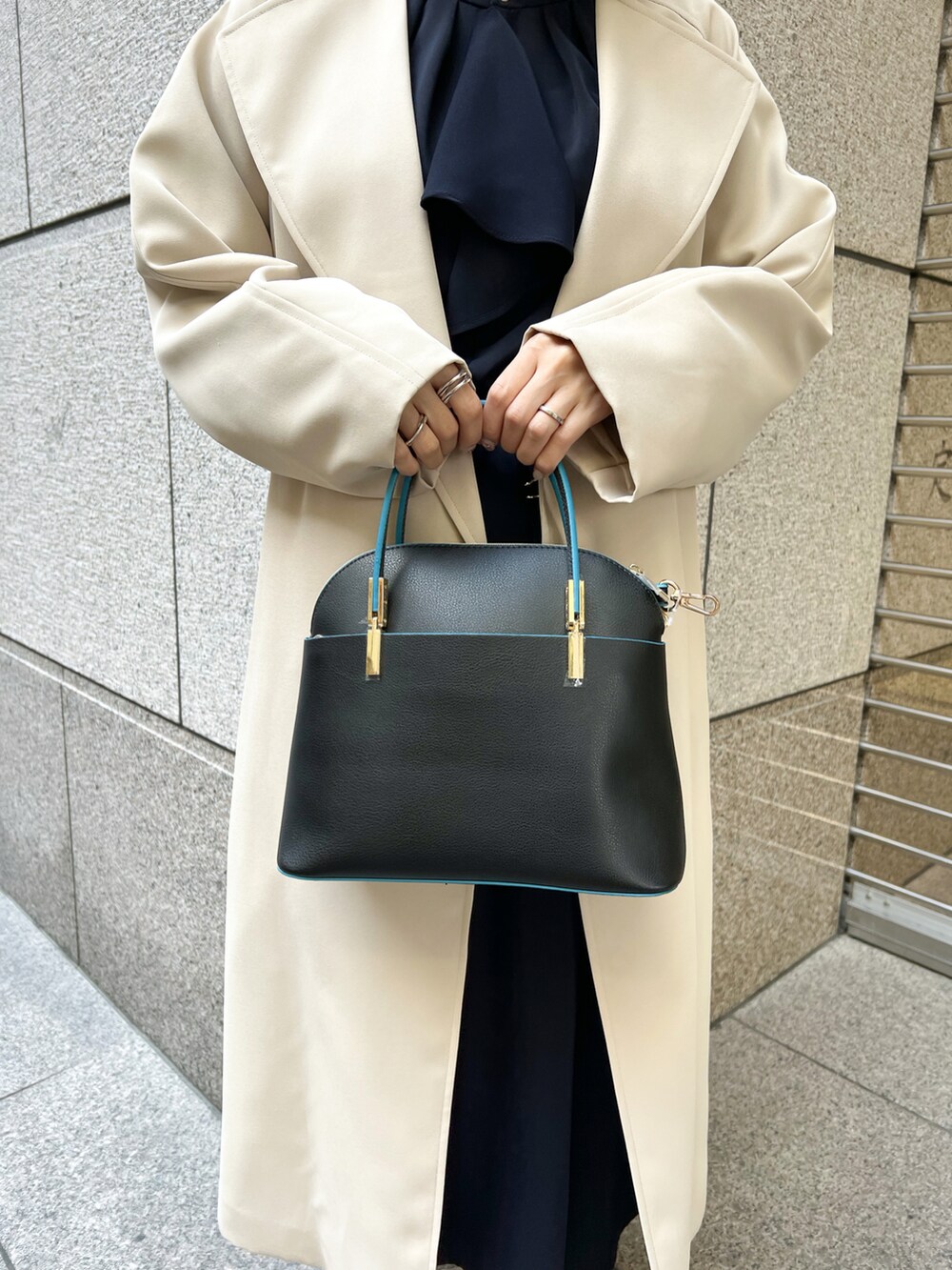 ブルー系のワンピース、ベージュ系のトレンチコート、ブラック系のショルダーバッグを着用したレディースの春コーディネートの5枚目の写真