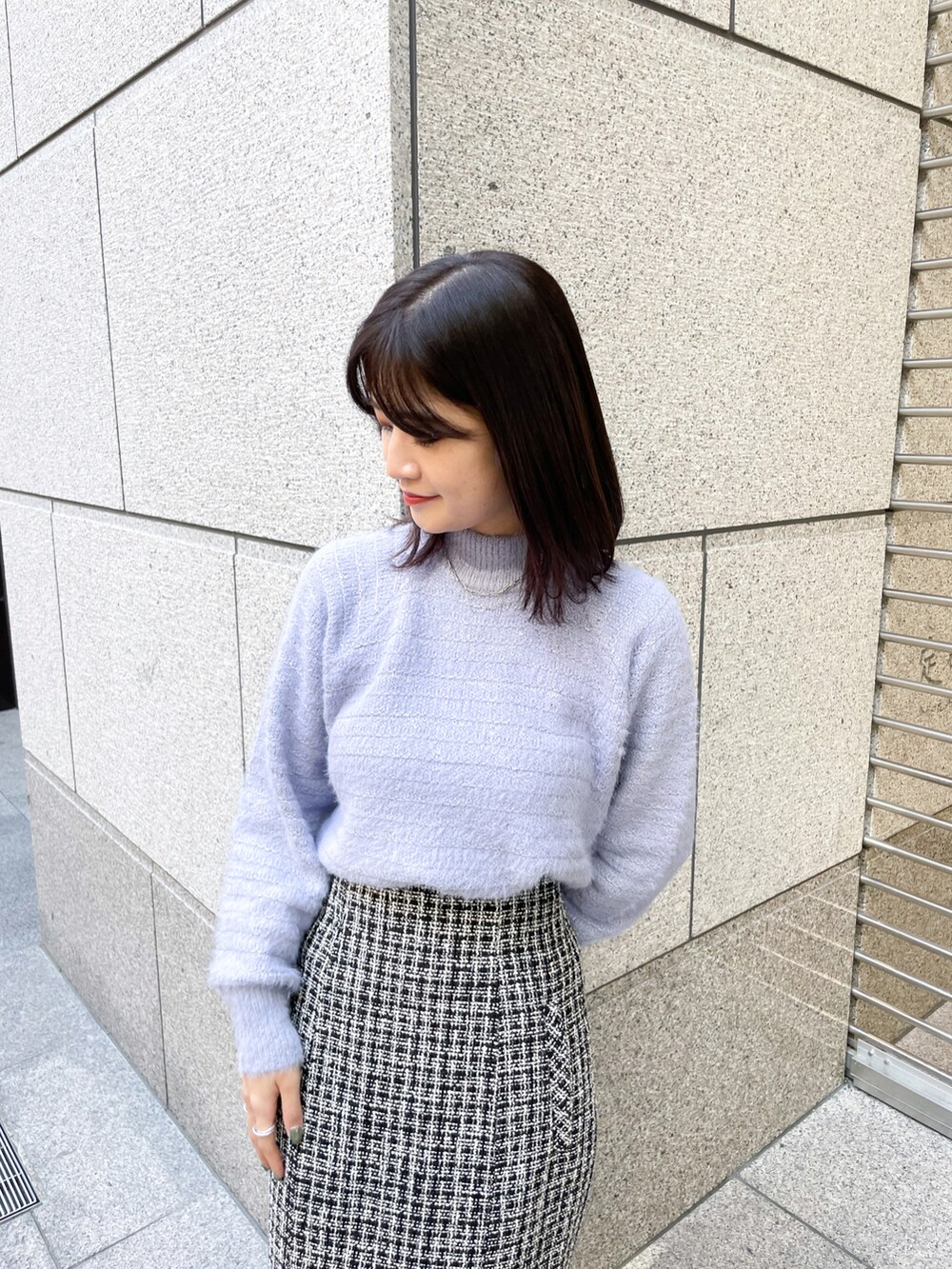 ブルー系のニット/セーター、ブラック系のスカート、ブラック系のトートバッグを着用したレディースの冬コーディネートの3枚目の写真