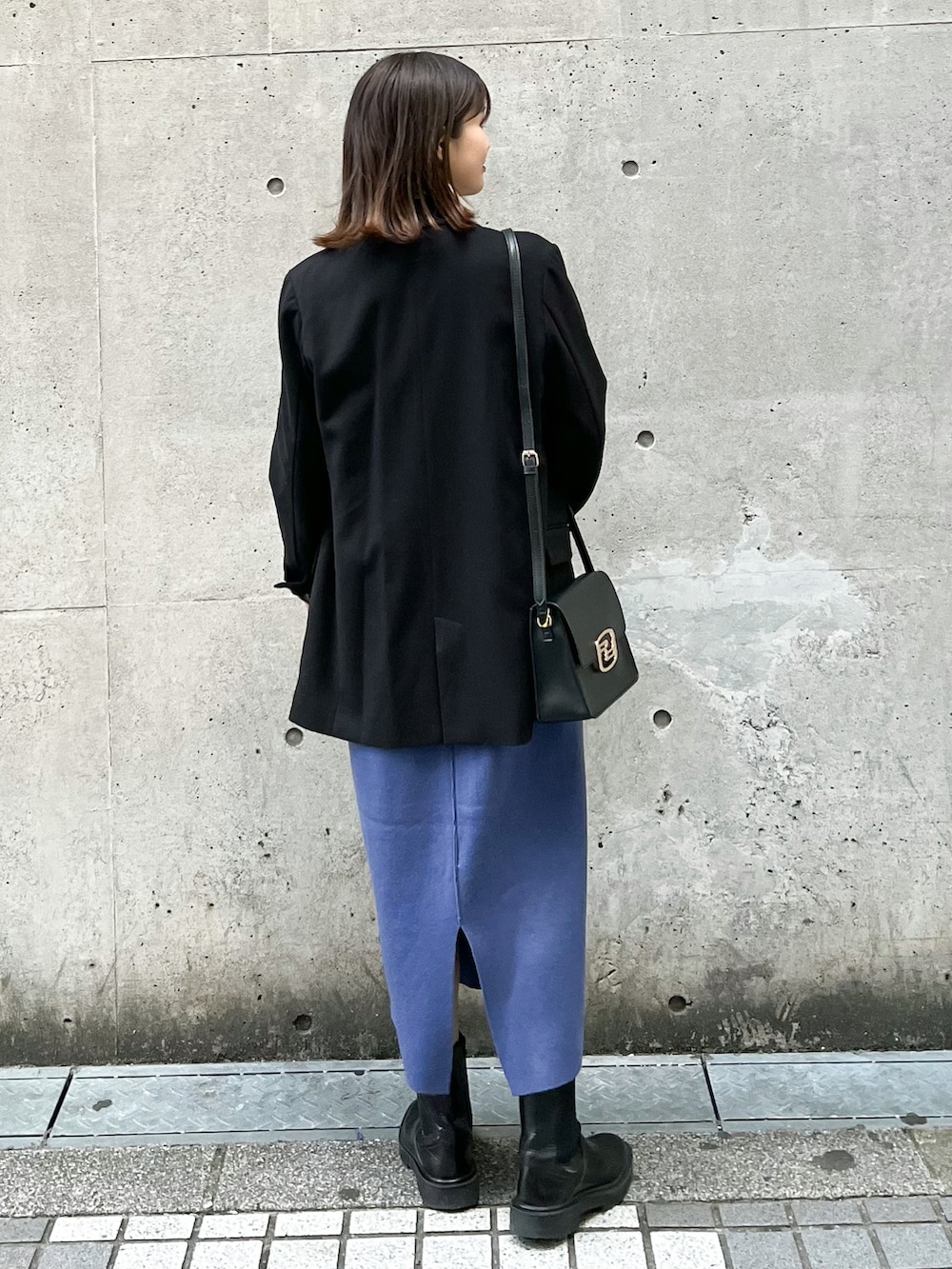 ブラック系のテーラードジャケット、ブルー系のジャンパースカート、ホワイト系のニット/セーターを着用したレディースの冬コーディネートの2枚目の写真