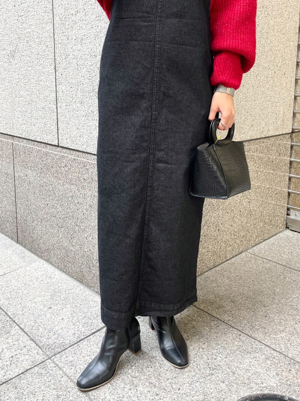 ピンク系のニット/セーター、ブラック系のジャンパースカート、ブラック系のブーツを着用したレディースの冬コーディネートの5枚目の写真