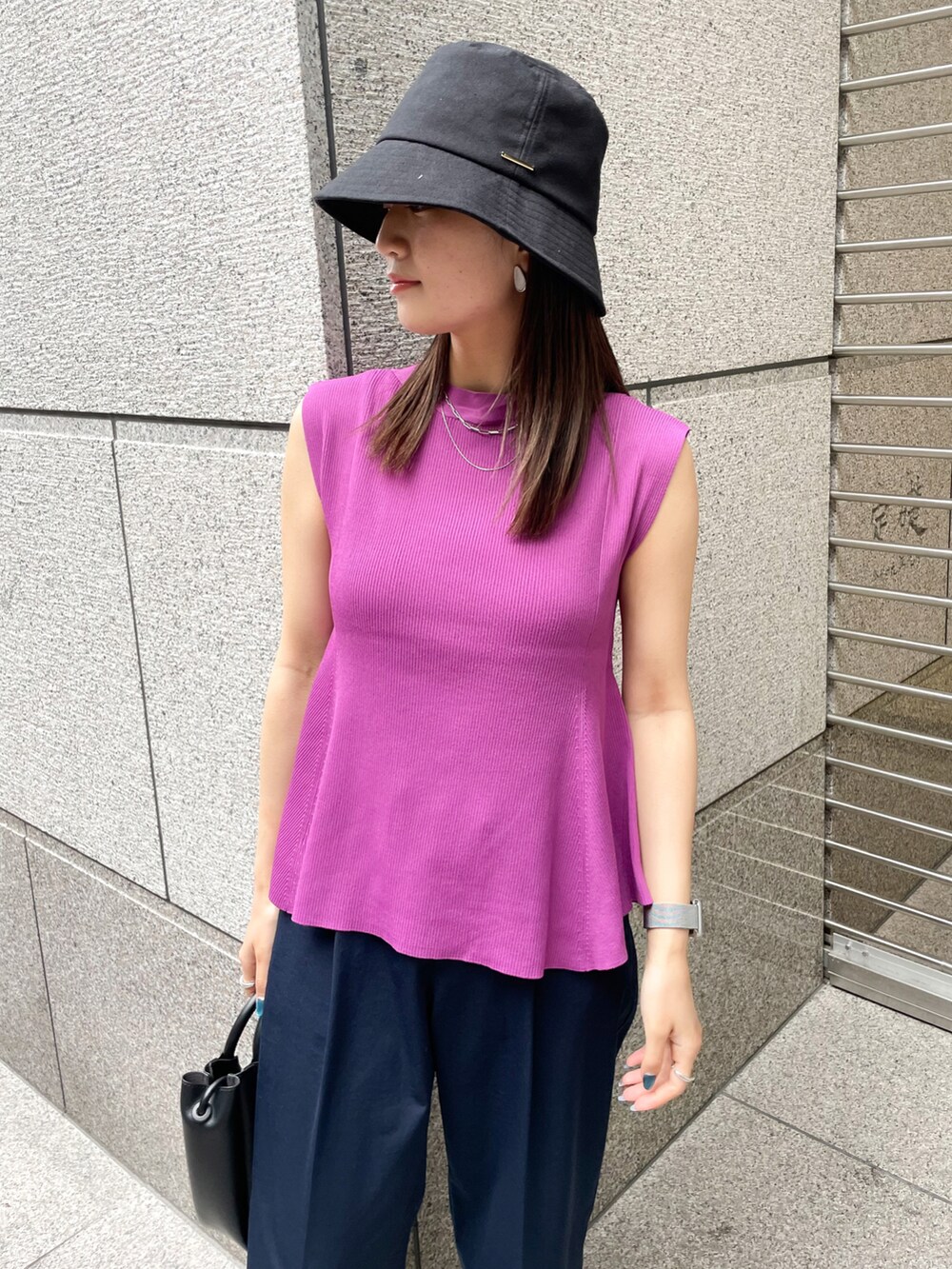 レッド系のニット/セーター、ブラック系のショルダーバッグ、ブルー系のチノパンツを着用したレディースの春コーディネートの3枚目の写真