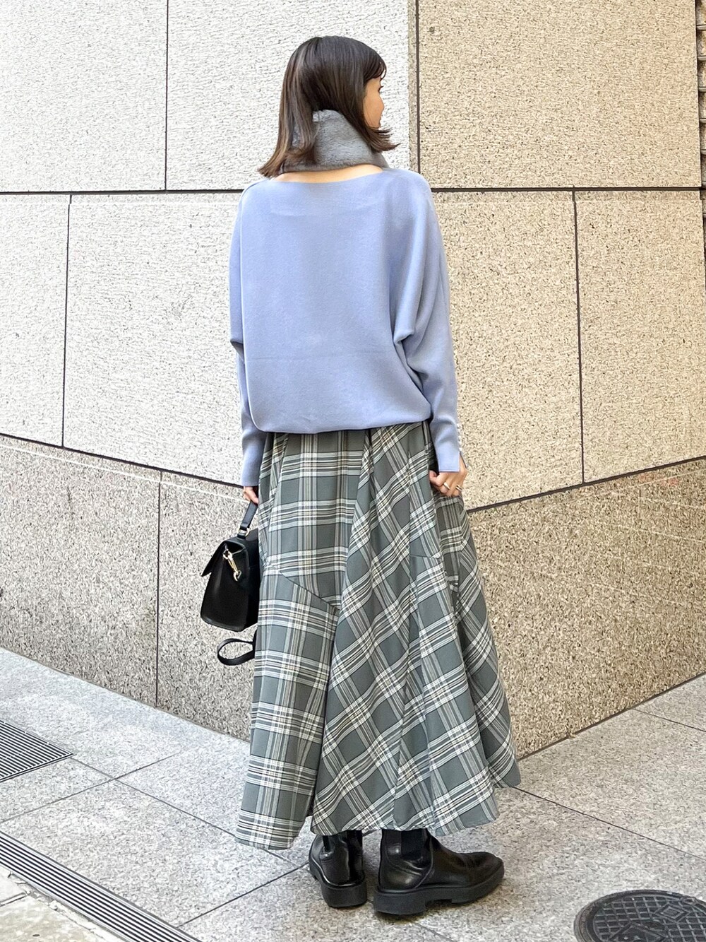 ブルー系のニット/セーター、ブラック系のショルダーバッグ、グレー系のスカートを着用したレディースの冬コーディネートの2枚目の写真