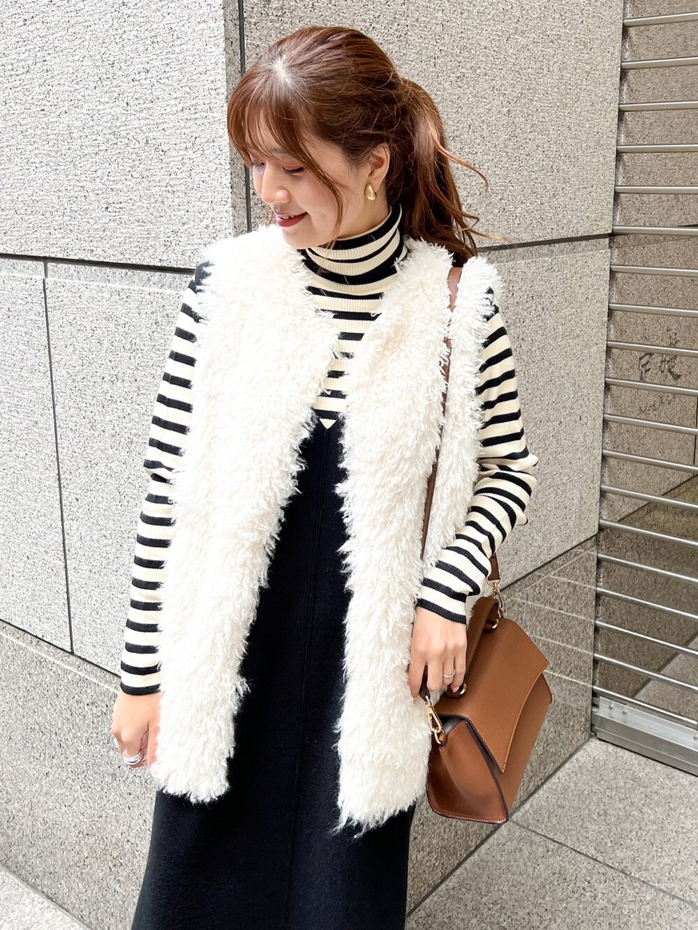 ブラック系のジャンパースカート、ホワイト系のニット/セーター、ホワイト系のベストを着用したレディースの秋コーディネートの4枚目の写真