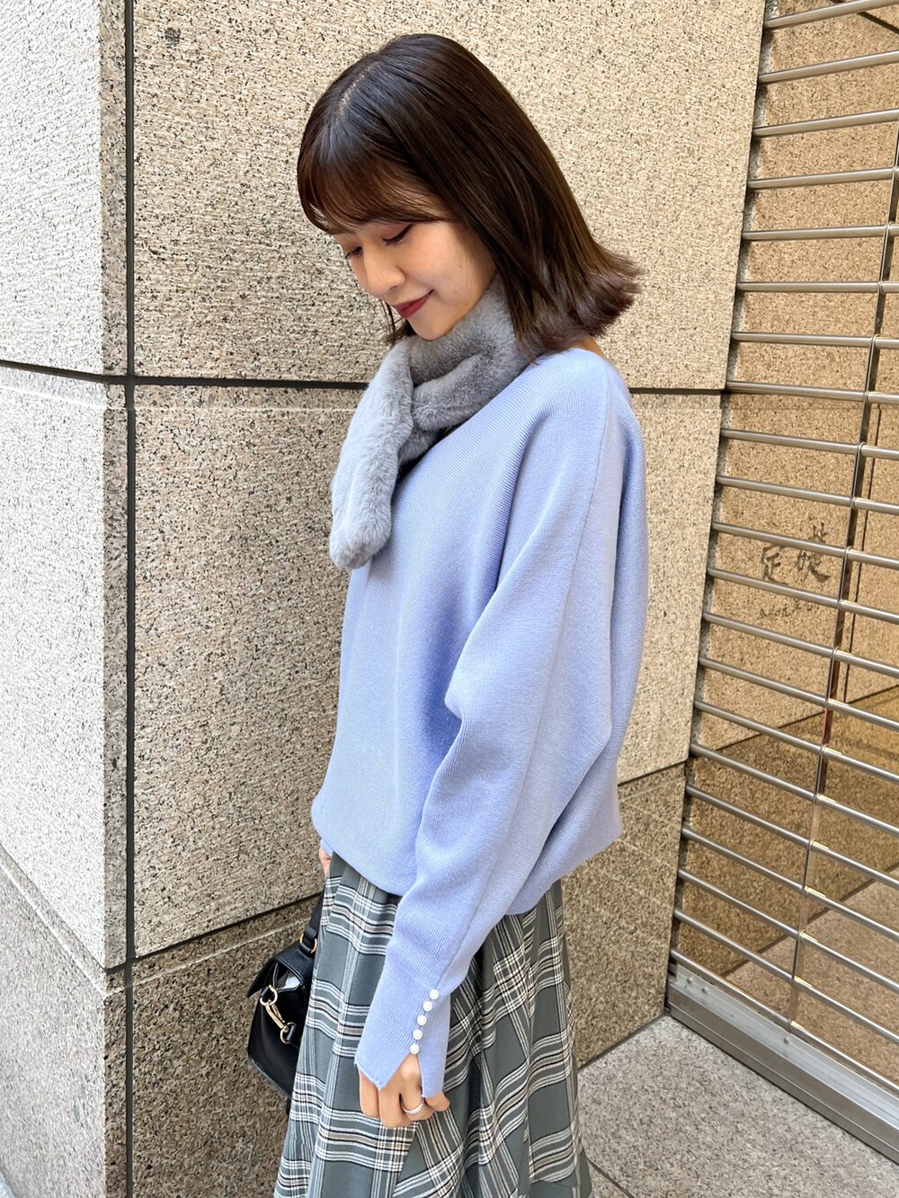 ブルー系のニット/セーター、ブラック系のショルダーバッグ、グレー系のスカートを着用したレディースの冬コーディネートの4枚目の写真