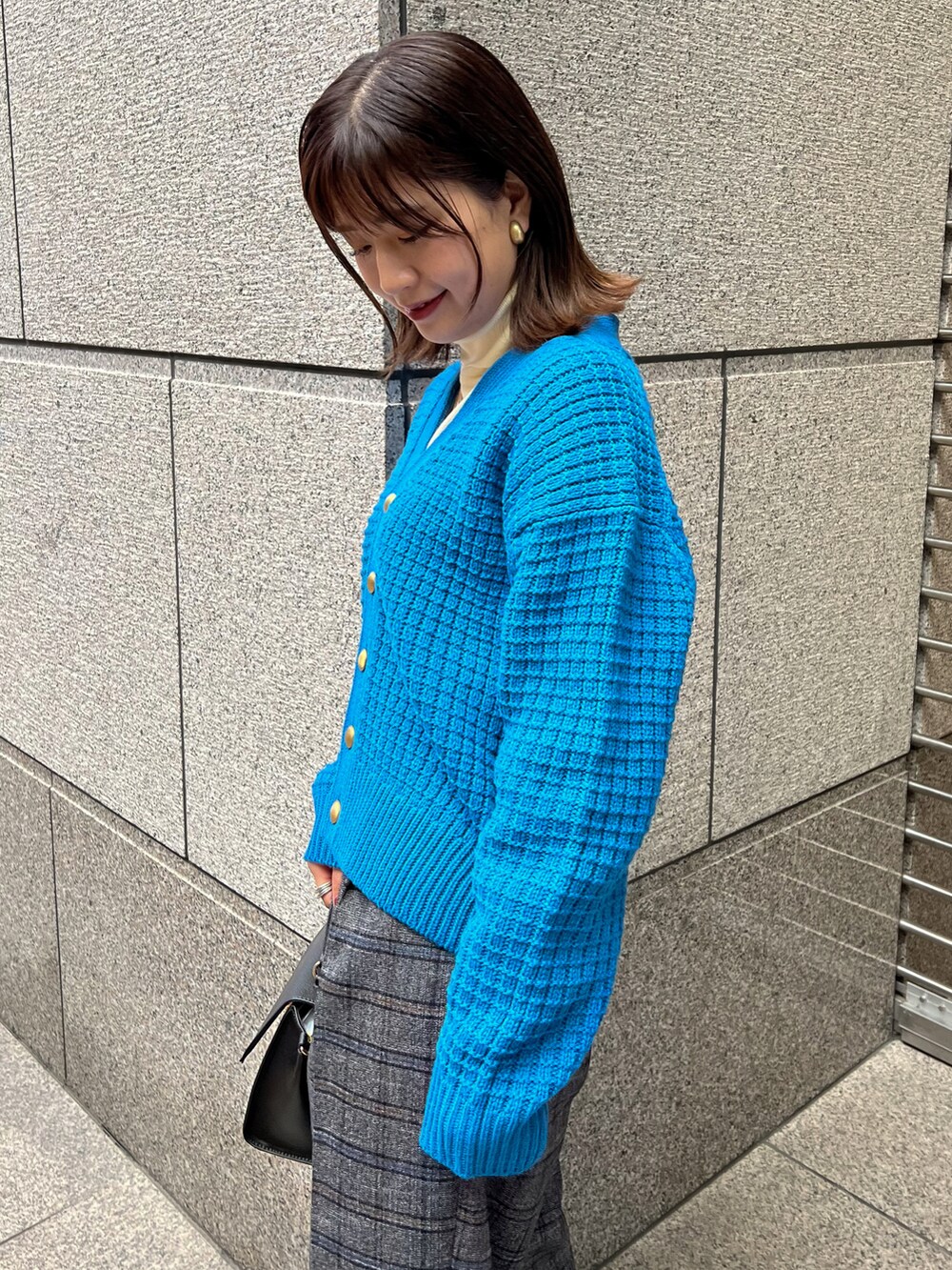 ブルー系のカーディガン/ボレロ、ホワイト系のニット/セーター、ブラック系のショルダーバッグを着用したレディースの冬コーディネートの4枚目の写真