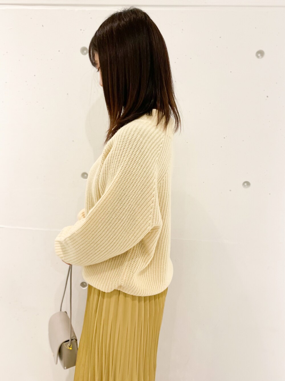 イエロー系のスカート、グレー系のショルダーバッグ、グレー系のローファーを着用したレディースの冬コーディネートの4枚目の写真