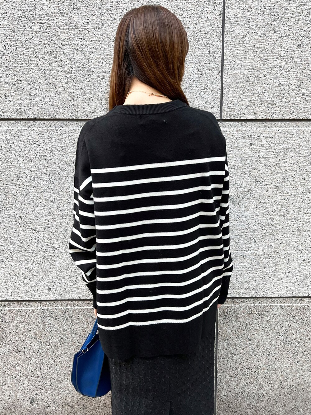 ブラック系のニット/セーター、ブルー系のショルダーバッグ、ブラック系のスカートを着用したレディースの冬コーディネートの5枚目の写真