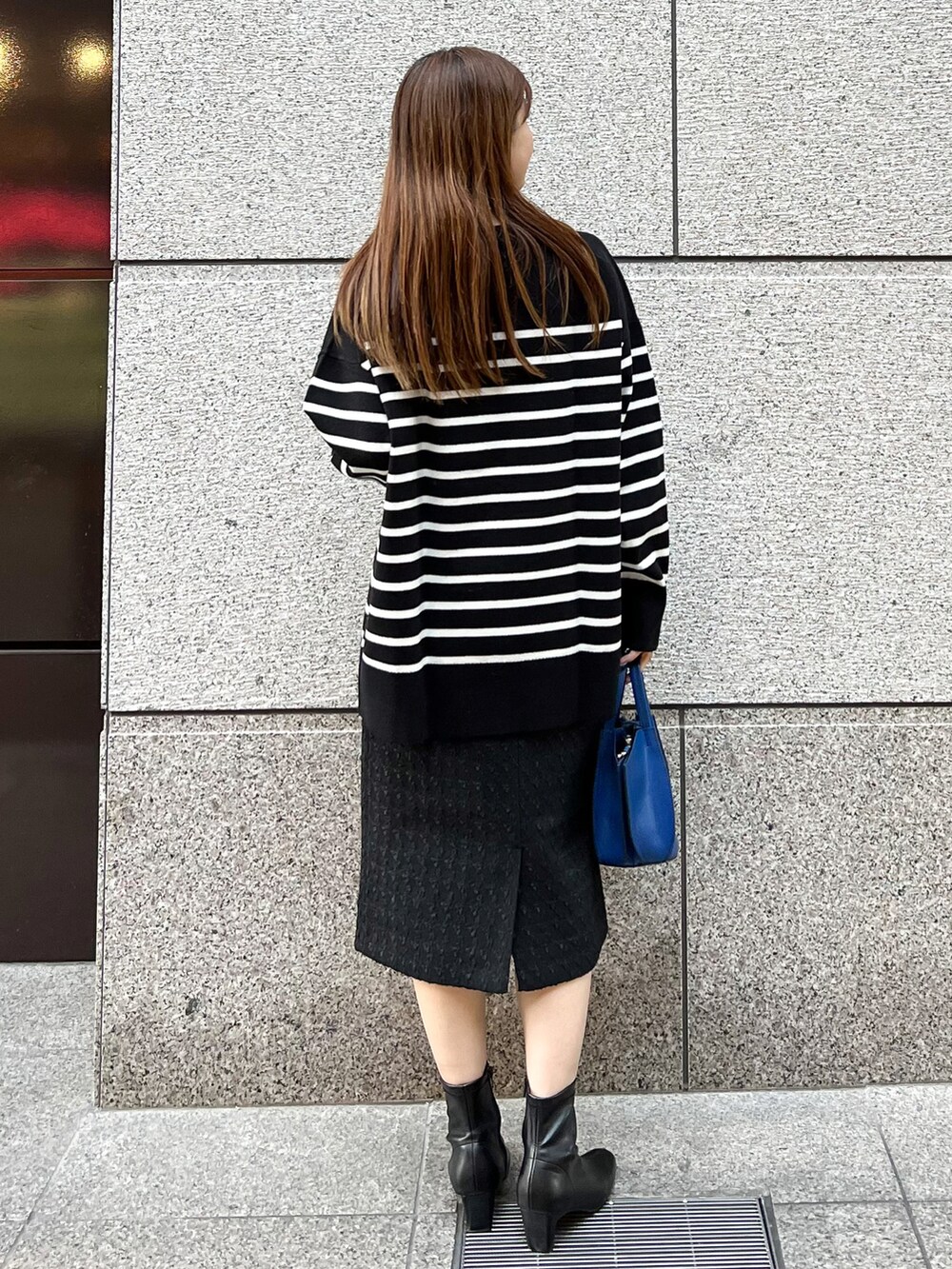 ブラック系のニット/セーター、ブルー系のショルダーバッグ、ブラック系のスカートを着用したレディースの冬コーディネートの2枚目の写真