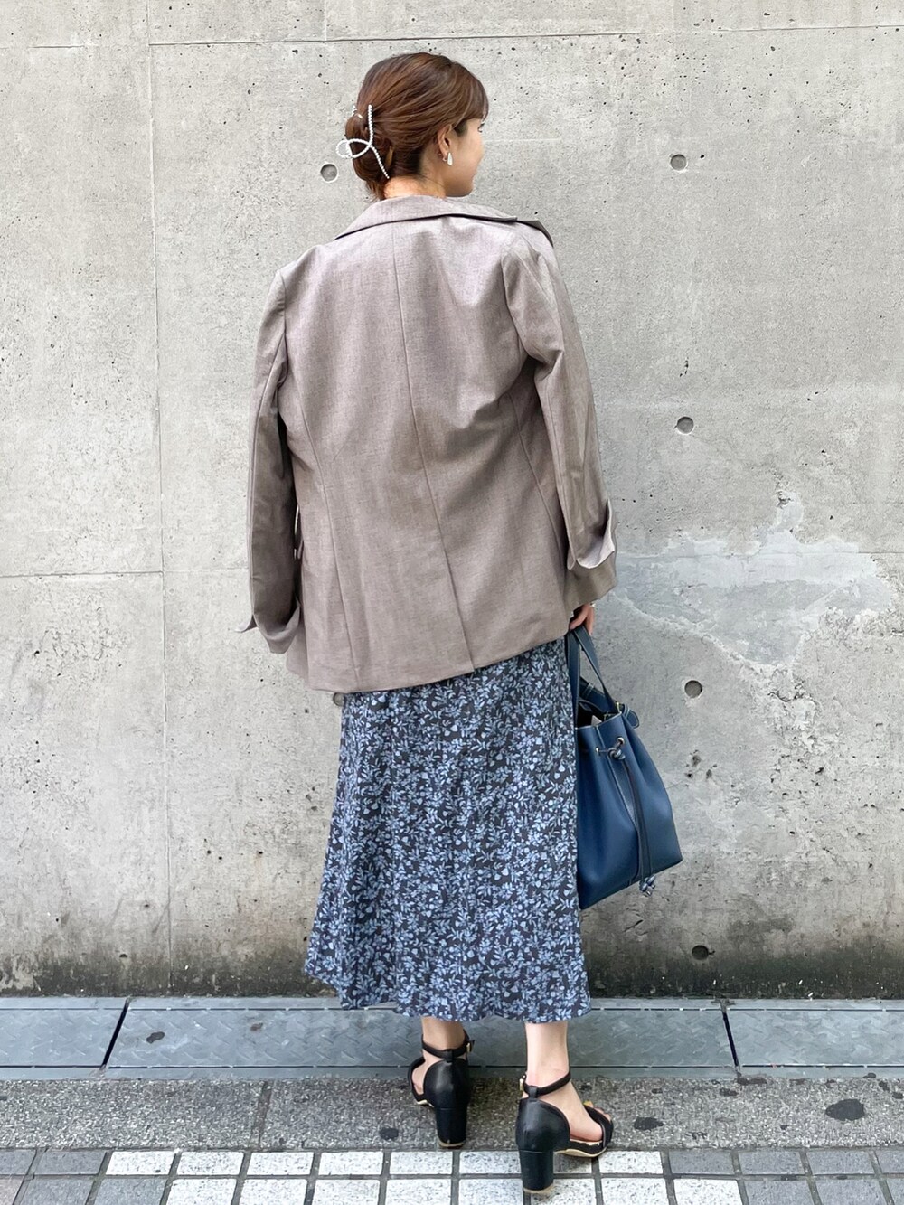 ベージュ系のテーラードジャケット、ブルー系のワンピース、ブルー系のトートバッグを着用したレディースの秋コーディネートの2枚目の写真