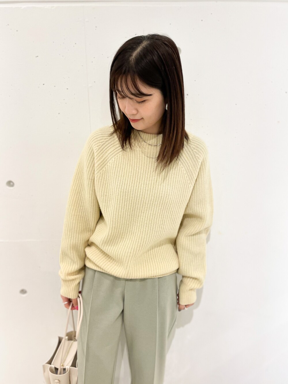 イエロー系のニット/セーター、グリーン系のその他パンツ、ホワイト系のショルダーバッグを着用したレディースの冬コーディネートの3枚目の写真