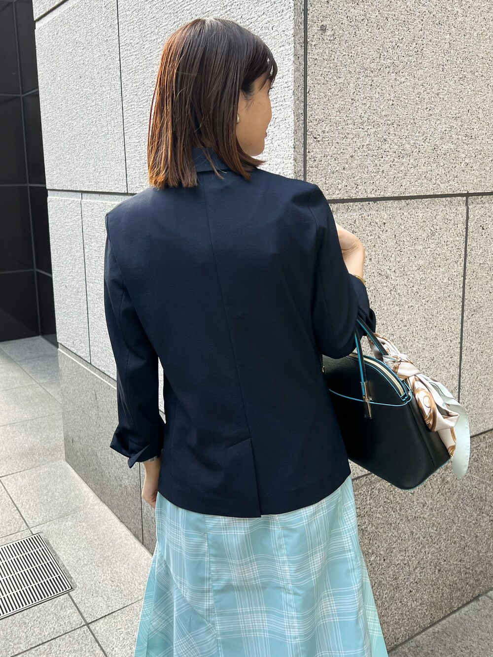 ブルー系のテーラードジャケット、ブラック系のショルダーバッグ、ブルー系のスカートを着用したレディースの春コーディネートの5枚目の写真