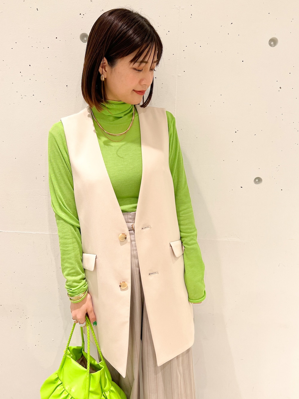 グリーン系のTシャツ/カットソー、ベージュ系のベスト、グリーン系のトートバッグを着用したレディースの春コーディネートの3枚目の写真