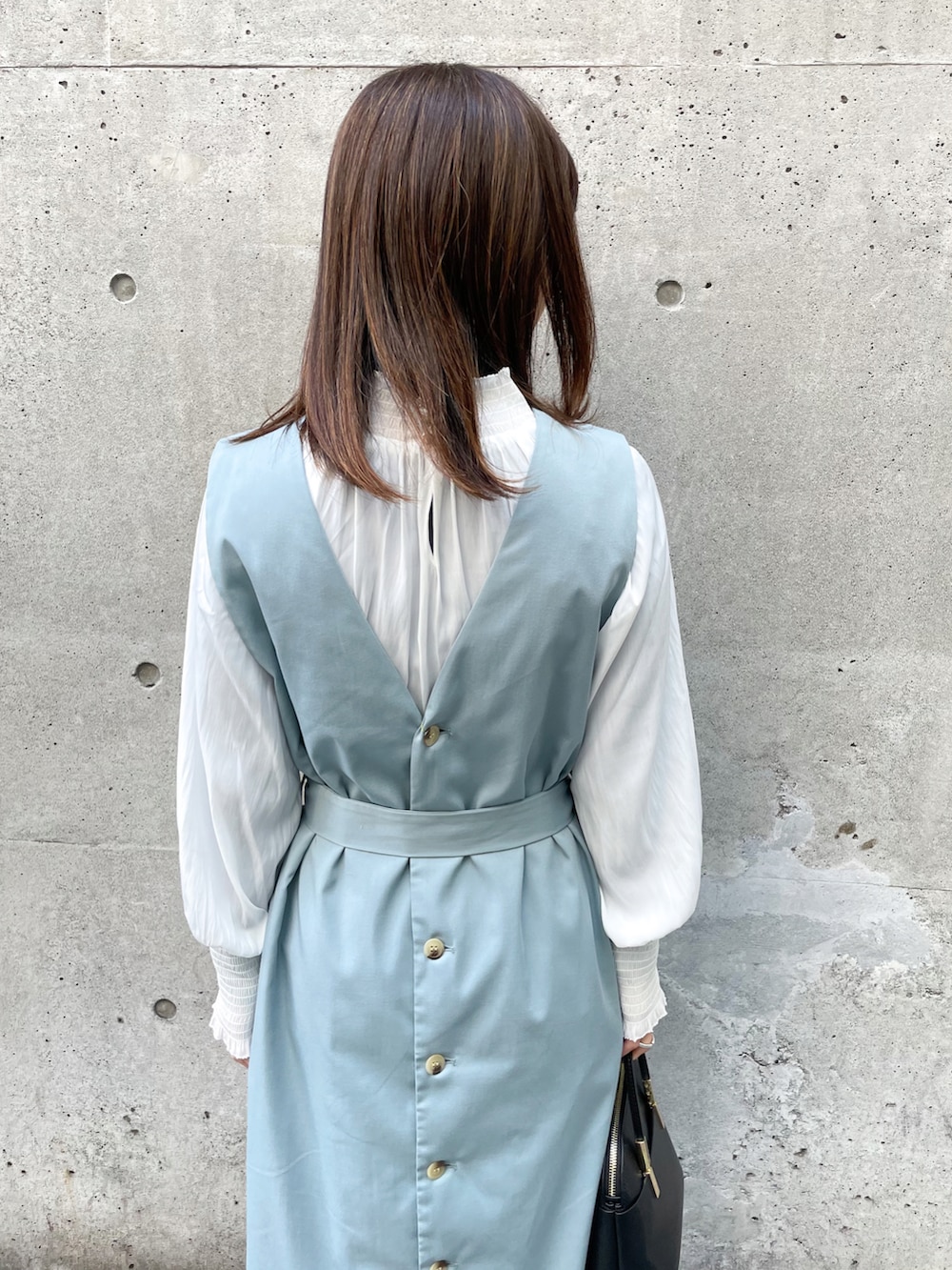 グリーン系のジャンパースカート、ブラック系のショルダーバッグ、ブラック系のその他シューズを着用したレディースの春コーディネートの5枚目の写真