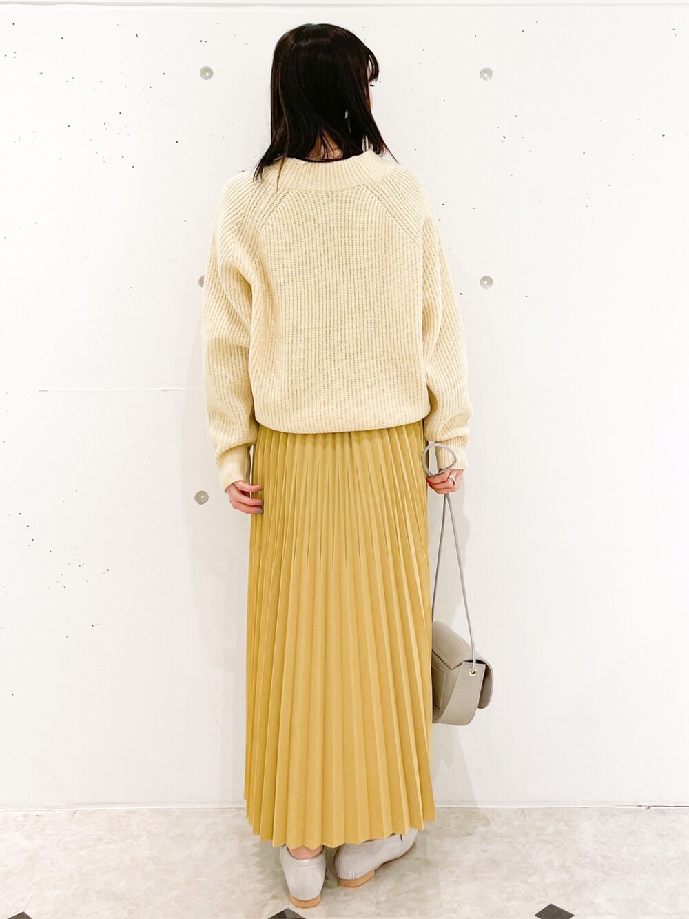 イエロー系のスカート、グレー系のショルダーバッグ、グレー系のローファーを着用したレディースの冬コーディネートの2枚目の写真