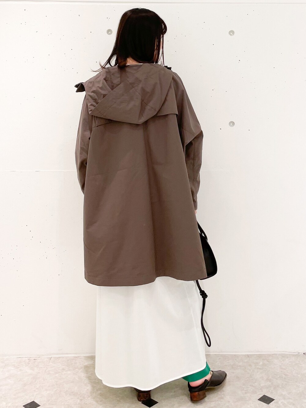 ブラウン系のマウンテンパーカー、ブラック系のショルダーバッグ、ホワイト系のワンピースを着用したレディースの冬コーディネートの2枚目の写真