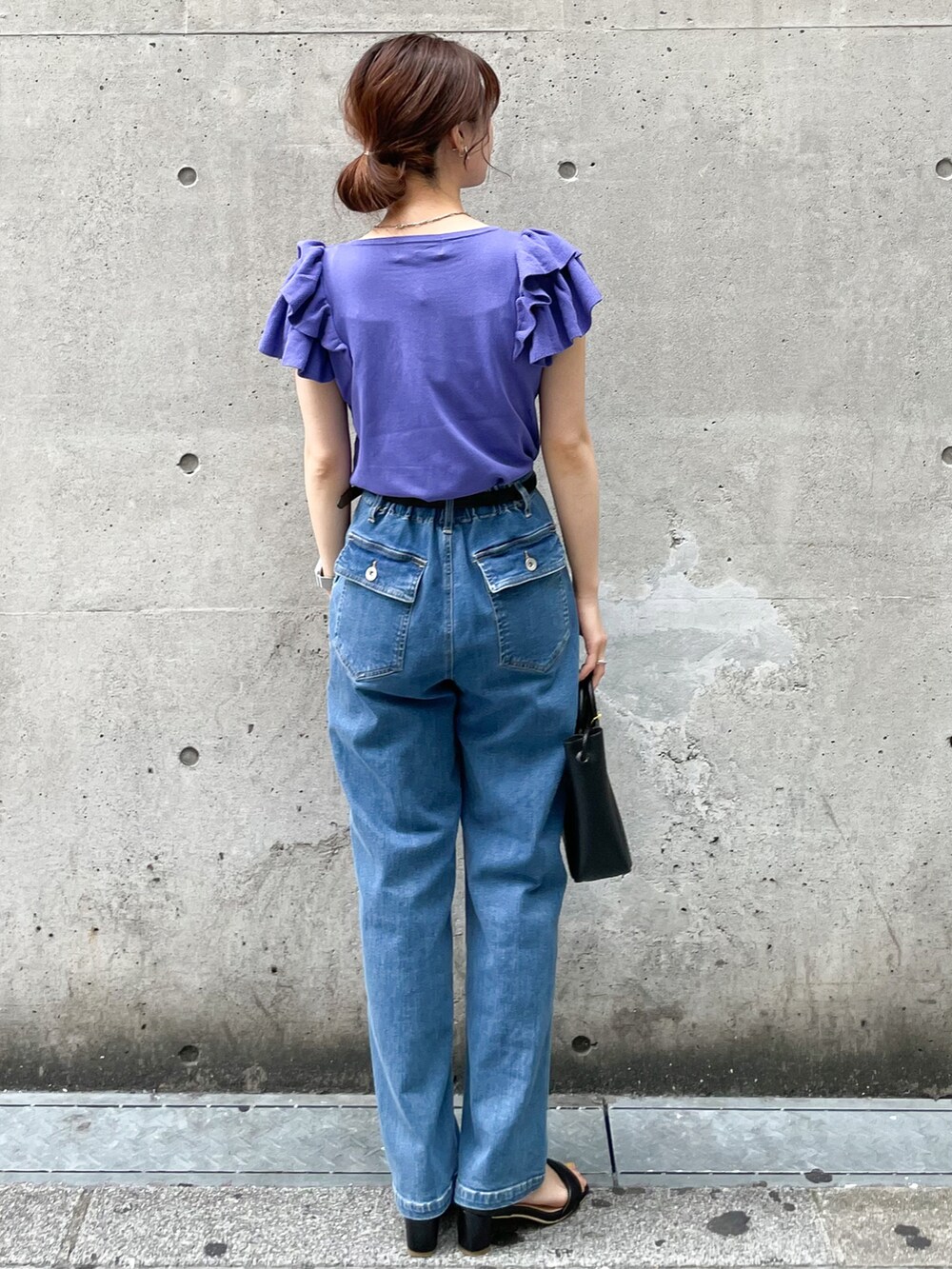 パープル系のニット/セーター、ブラック系のショルダーバッグ、ブルー系のデニムパンツを着用したレディースの春コーディネートの2枚目の写真