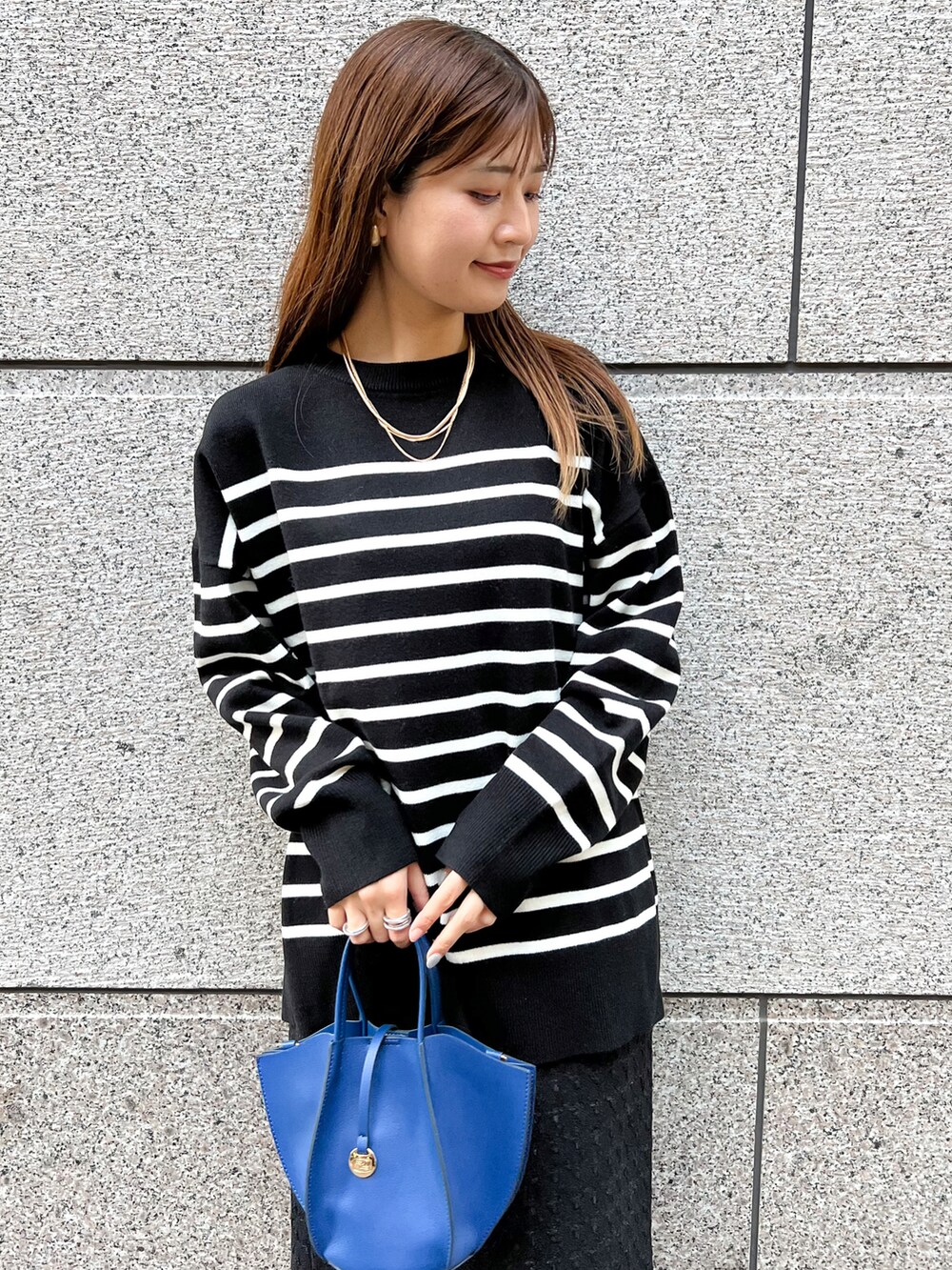 ブラック系のニット/セーター、ブルー系のショルダーバッグ、ブラック系のスカートを着用したレディースの冬コーディネートの4枚目の写真
