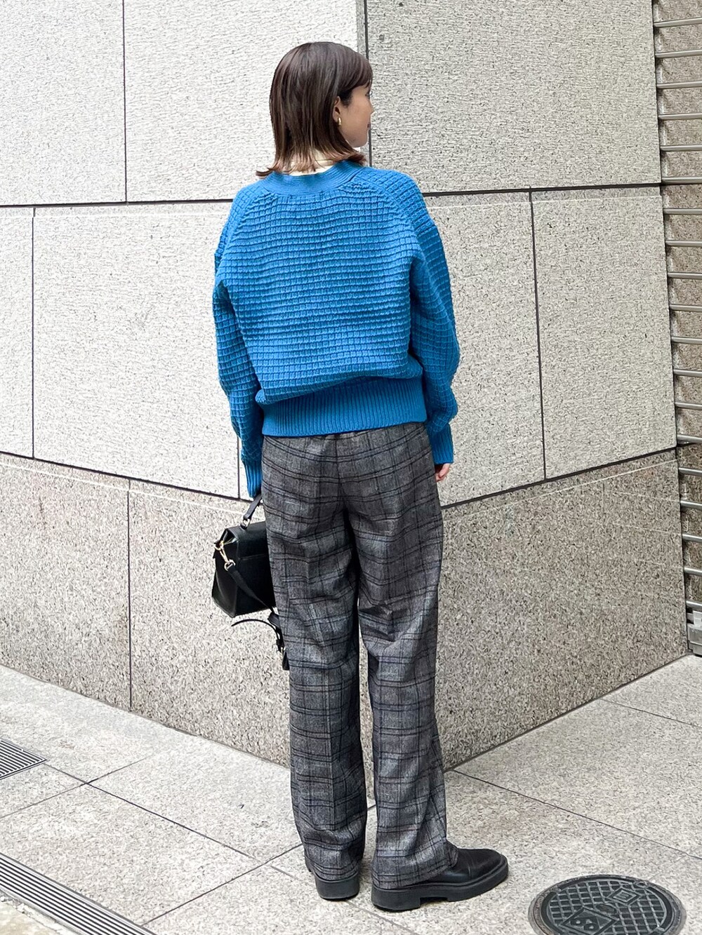 ブルー系のカーディガン/ボレロ、ホワイト系のニット/セーター、ブラック系のショルダーバッグを着用したレディースの冬コーディネートの2枚目の写真