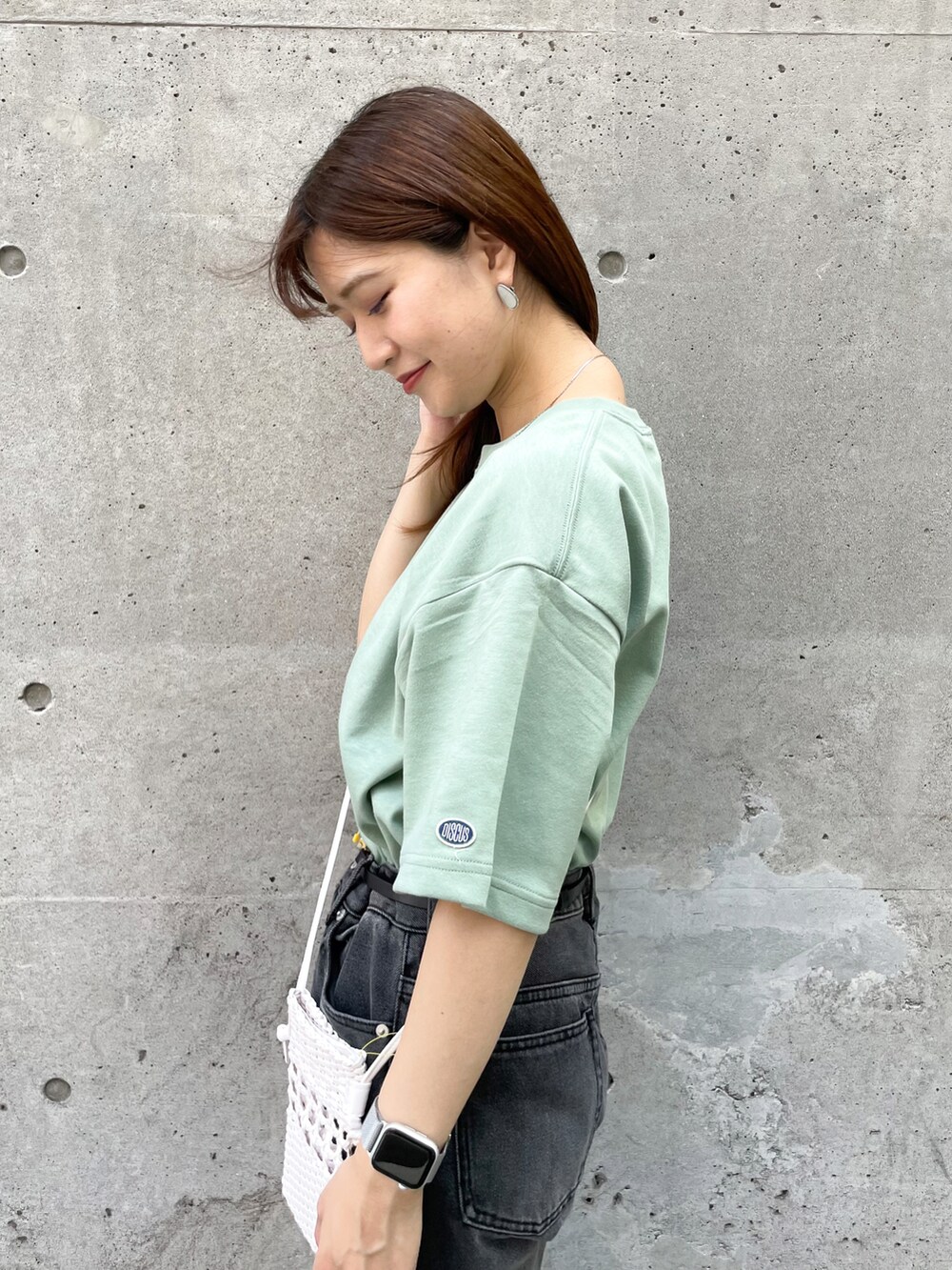 グリーン系のTシャツ/カットソー、ホワイト系のショルダーバッグ、ブラック系のデニムパンツを着用したレディースの夏コーディネートの3枚目の写真