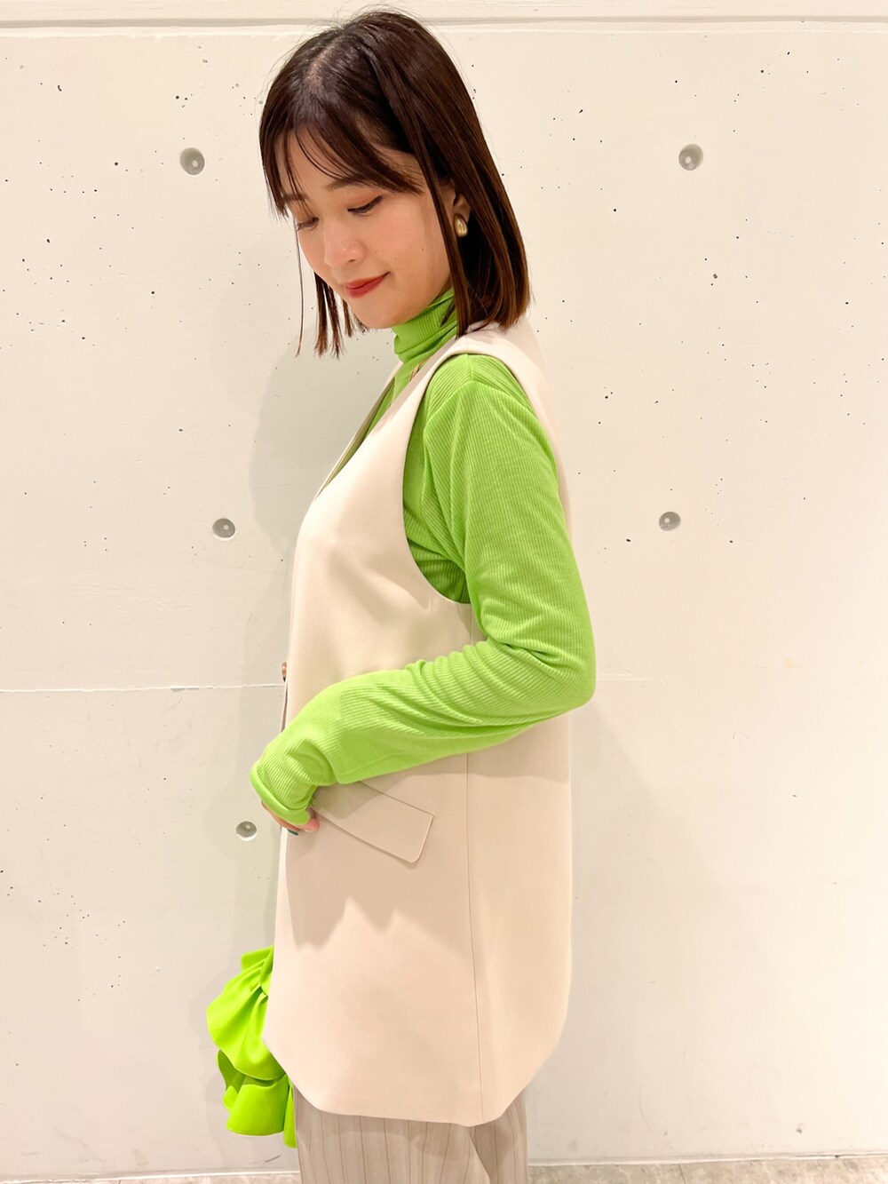 グリーン系のTシャツ/カットソー、ベージュ系のベスト、グリーン系のトートバッグを着用したレディースの春コーディネートの4枚目の写真