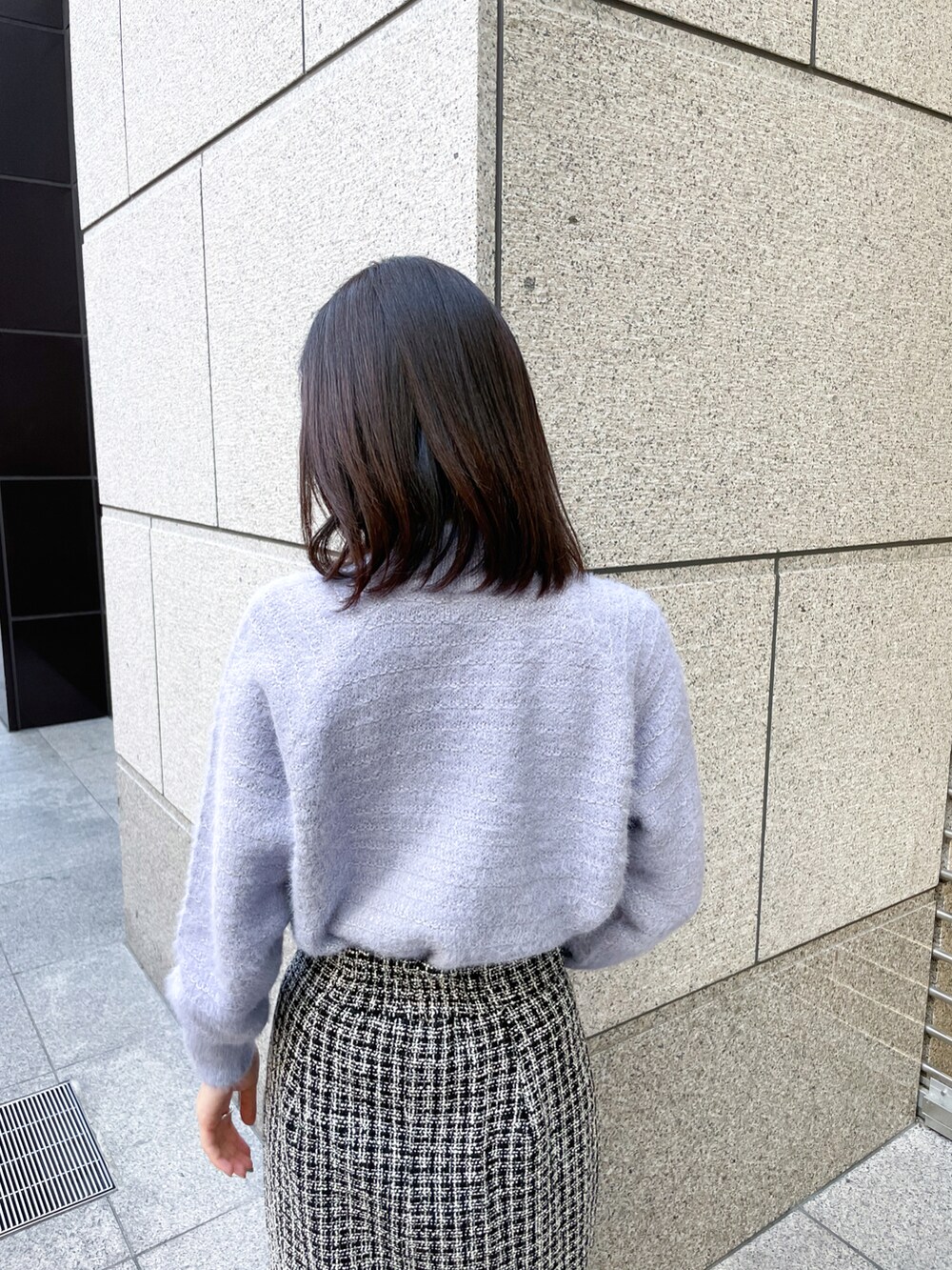 ブルー系のニット/セーター、ブラック系のスカート、ブラック系のトートバッグを着用したレディースの冬コーディネートの4枚目の写真