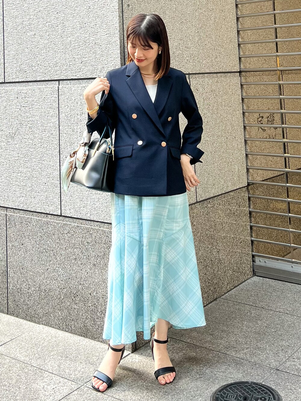 ブルー系のテーラードジャケット、ブラック系のショルダーバッグ、ブルー系のスカートを着用したレディースの春コーディネートの2枚目の写真