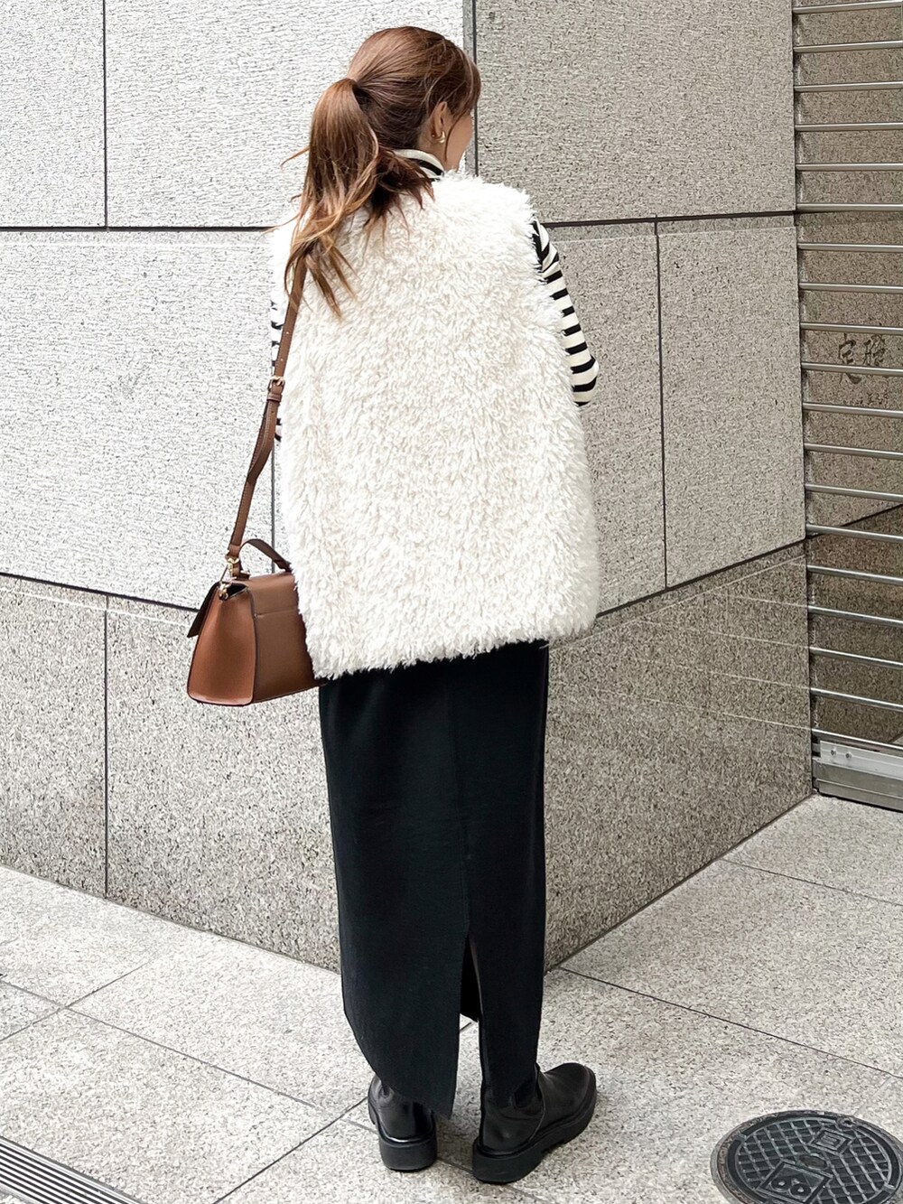 ブラック系のジャンパースカート、ホワイト系のニット/セーター、ホワイト系のベストを着用したレディースの秋コーディネートの3枚目の写真