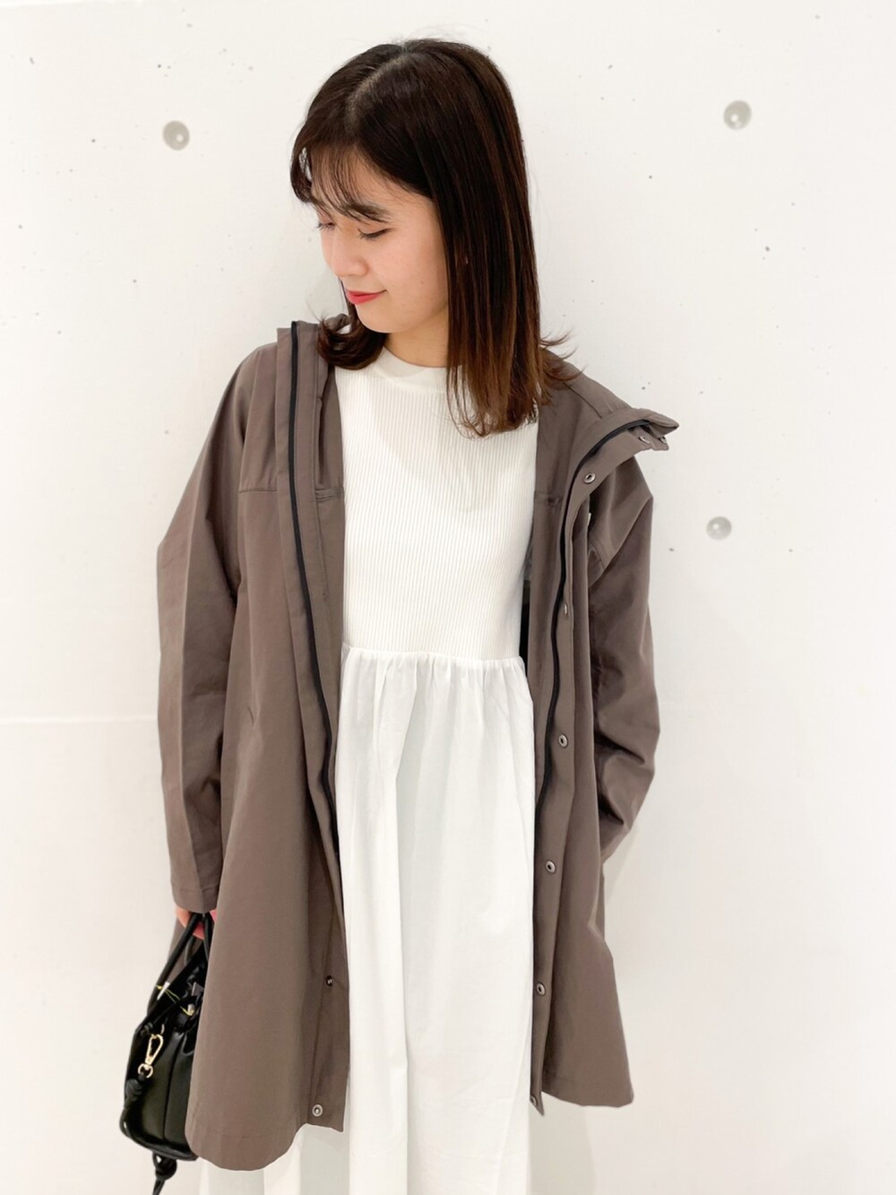 ブラウン系のマウンテンパーカー、ブラック系のショルダーバッグ、ホワイト系のワンピースを着用したレディースの冬コーディネートの3枚目の写真