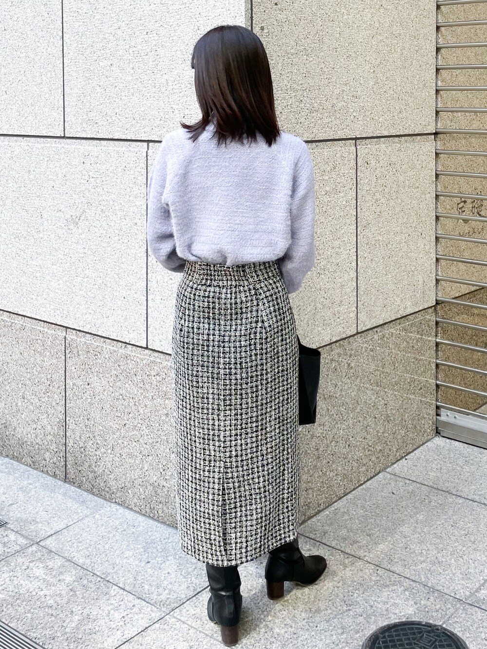 ブルー系のニット/セーター、ブラック系のスカート、ブラック系のトートバッグを着用したレディースの冬コーディネートの2枚目の写真