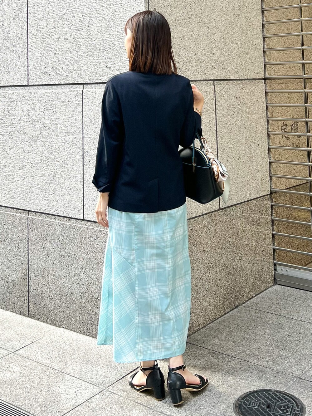ブルー系のテーラードジャケット、ブラック系のショルダーバッグ、ブルー系のスカートを着用したレディースの春コーディネートの3枚目の写真