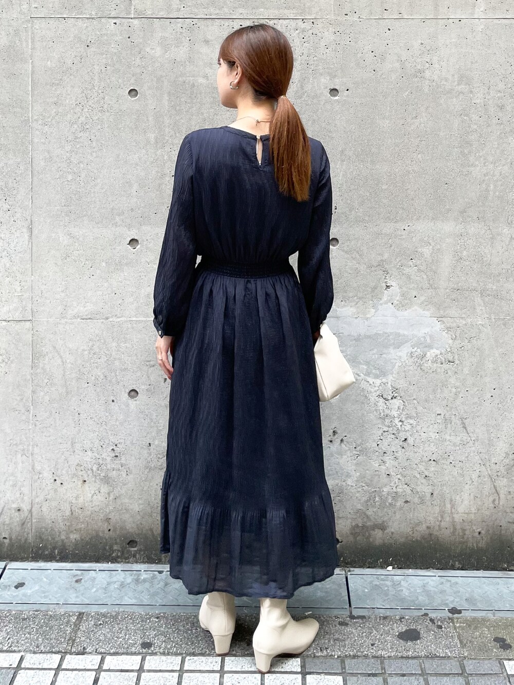 ブルー系のワンピース、ホワイト系のショルダーバッグ、ホワイト系のブーツを着用したレディースの秋コーディネートの2枚目の写真