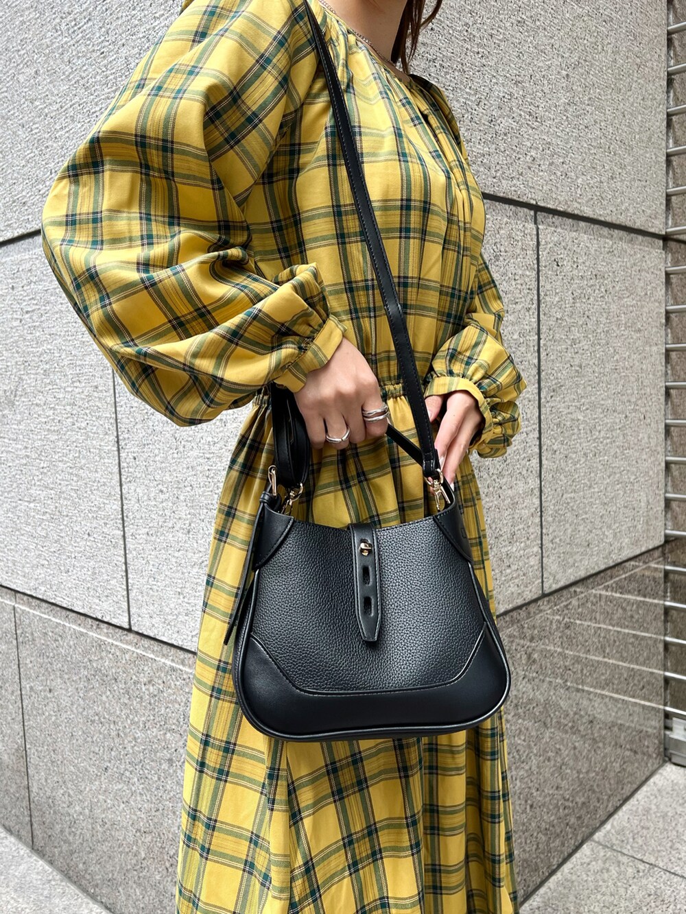 イエロー系のワンピース、ブラック系のショルダーバッグ、ブラック系のブーツを着用したレディースの秋コーディネートの4枚目の写真