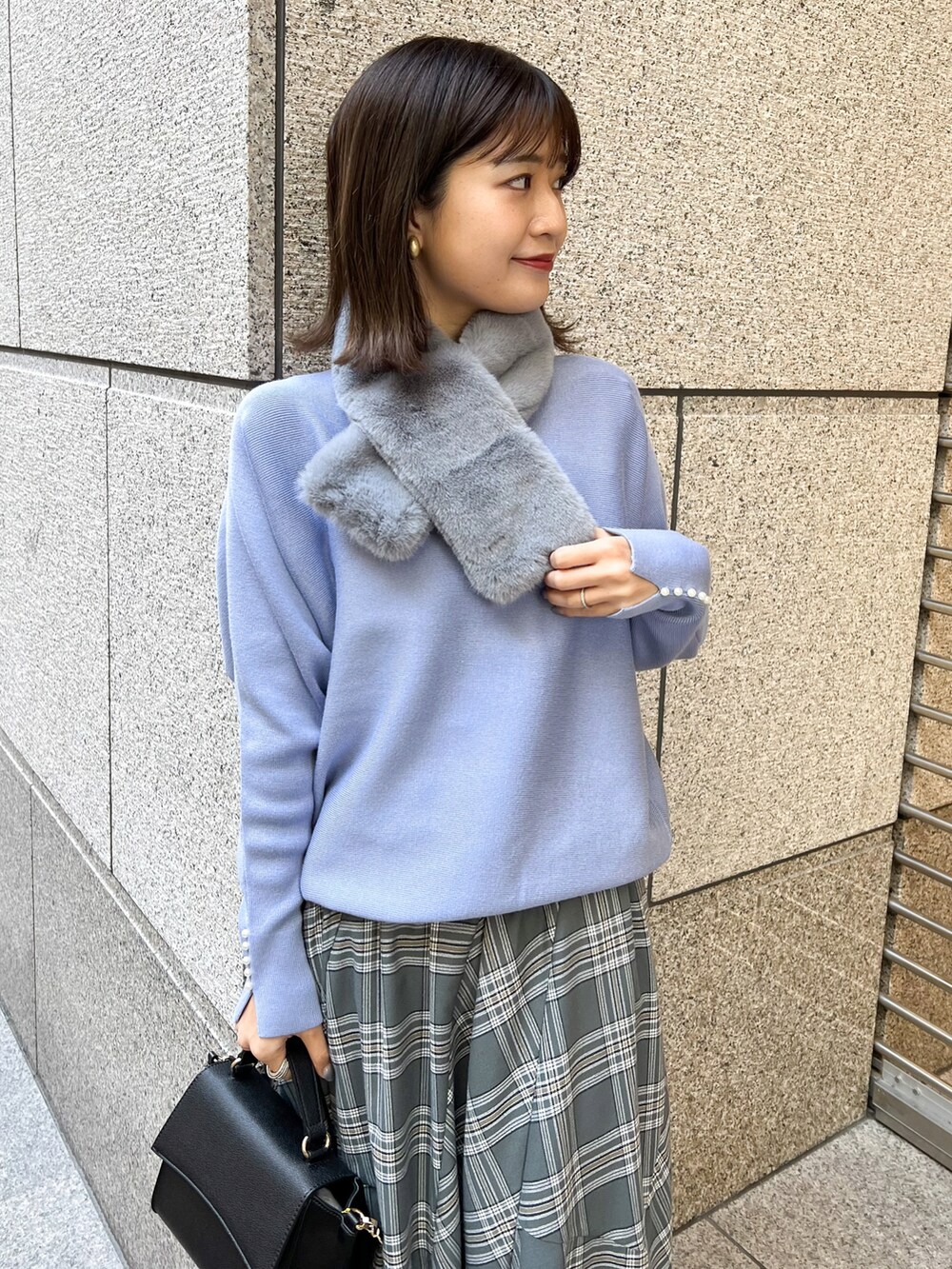 ブルー系のニット/セーター、ブラック系のショルダーバッグ、グレー系のスカートを着用したレディースの冬コーディネートの3枚目の写真