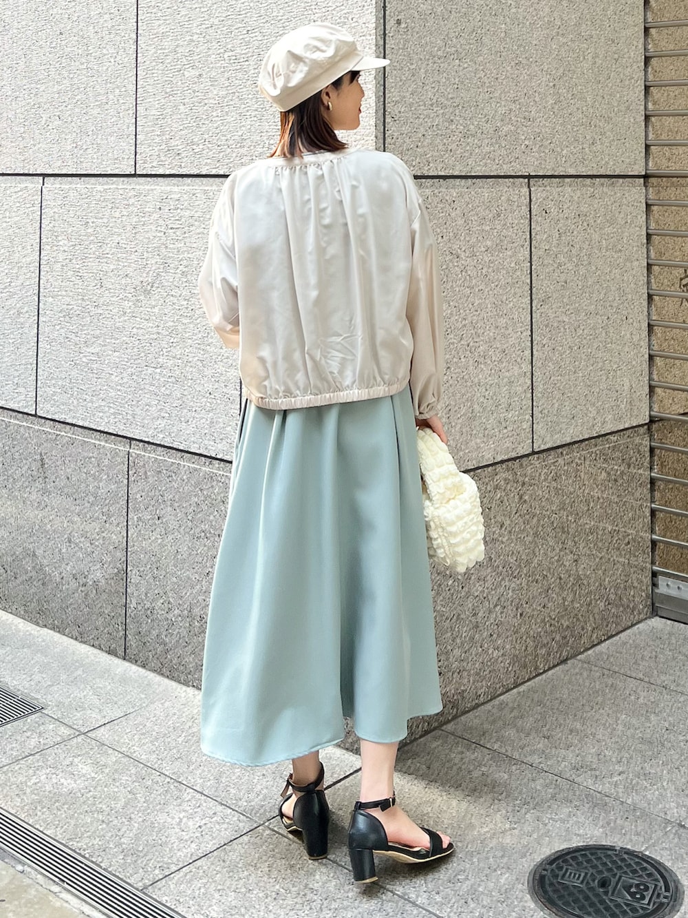 ベージュ系のブルゾン、グリーン系のワンピース、ホワイト系のショルダーバッグを着用したレディースの春コーディネートの2枚目の写真