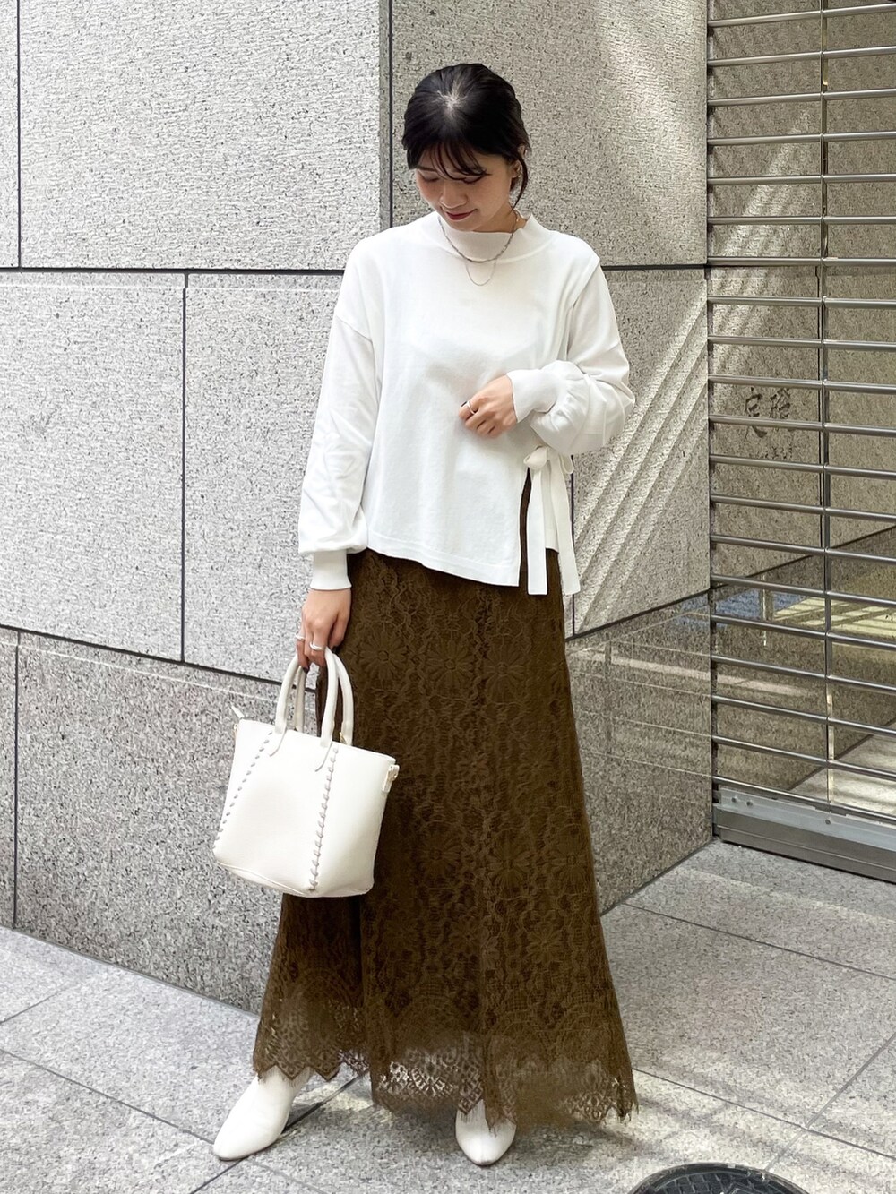 ホワイト系のニット/セーター、グリーン系のスカート、ホワイト系のショルダーバッグを着用したレディースの冬コーディネートの2枚目の写真