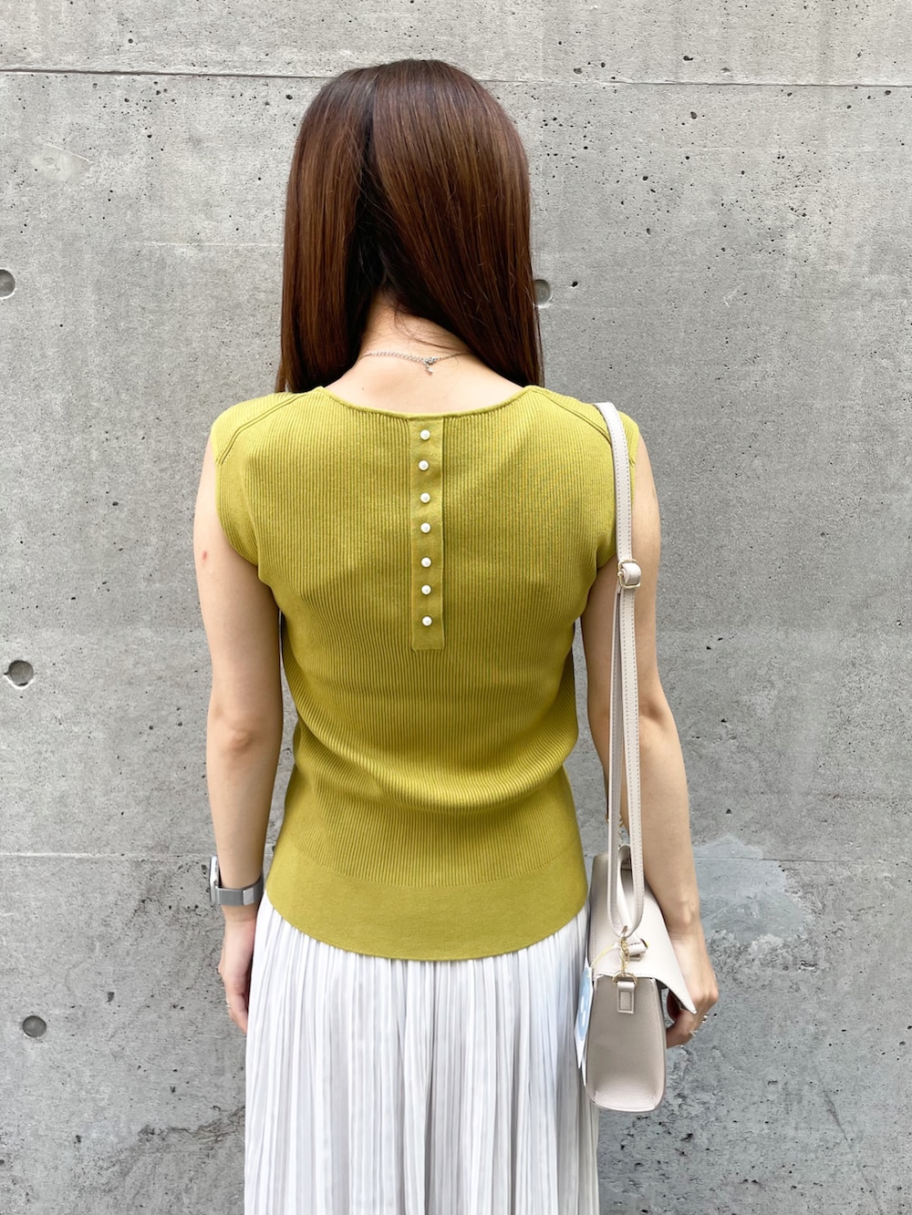 イエロー系のニット/セーター、ベージュ系のショルダーバッグ、グレー系のスカートを着用したレディースの夏コーディネートの5枚目の写真