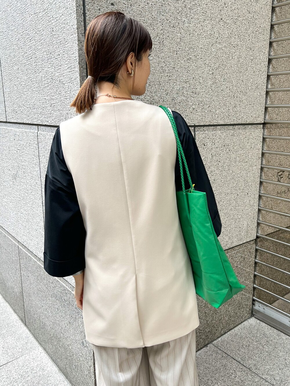 ブラック系のTシャツ/カットソー、ベージュ系のベスト、グリーン系のトートバッグを着用したレディースの春コーディネートの5枚目の写真