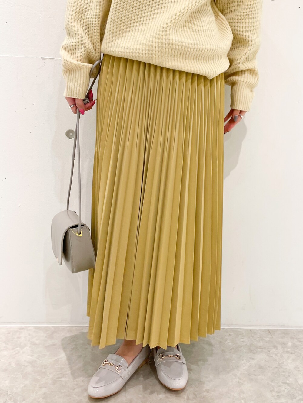 イエロー系のスカート、グレー系のショルダーバッグ、グレー系のローファーを着用したレディースの冬コーディネートの5枚目の写真