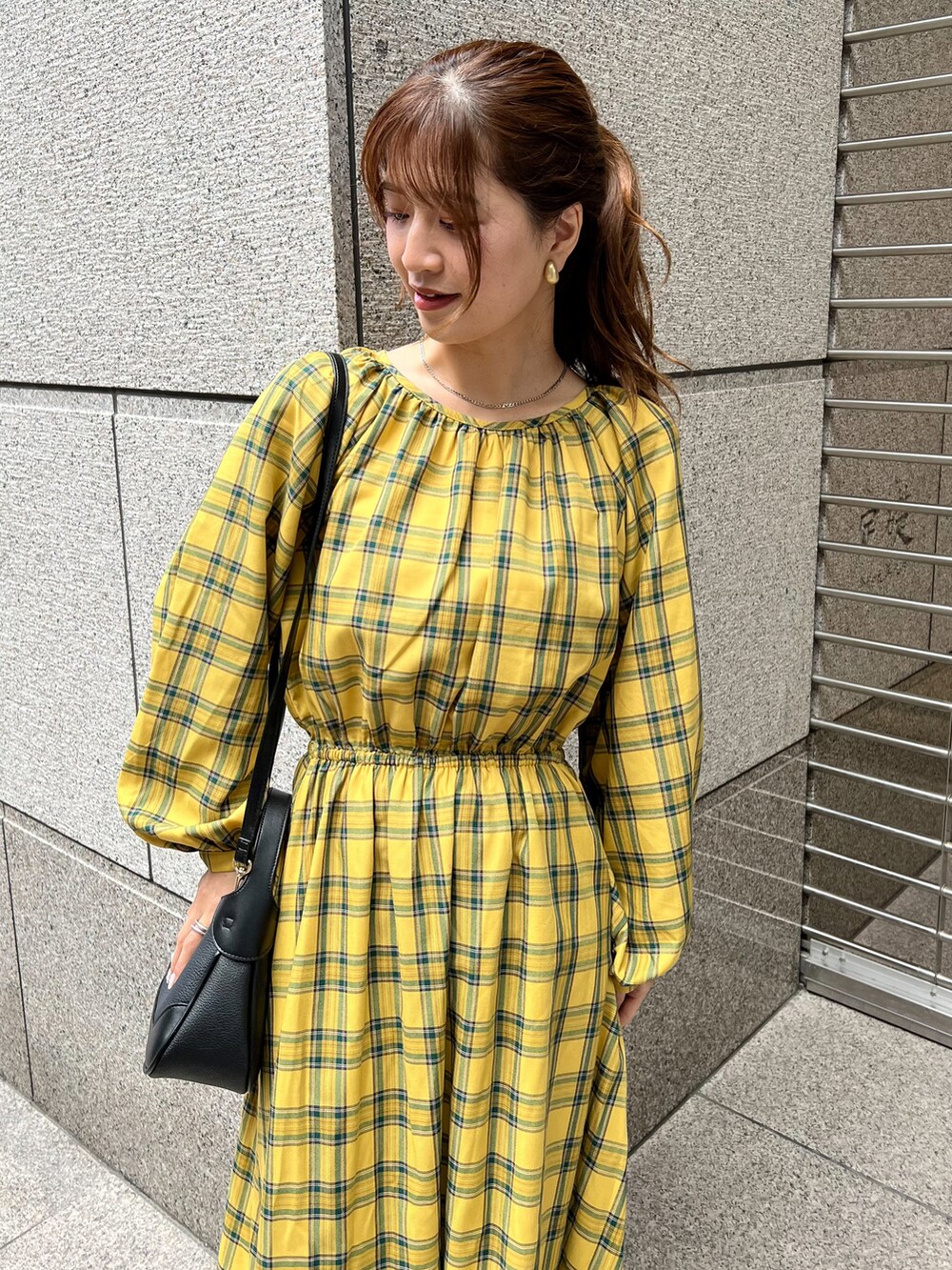 イエロー系のワンピース、ブラック系のショルダーバッグ、ブラック系のブーツを着用したレディースの秋コーディネートの3枚目の写真