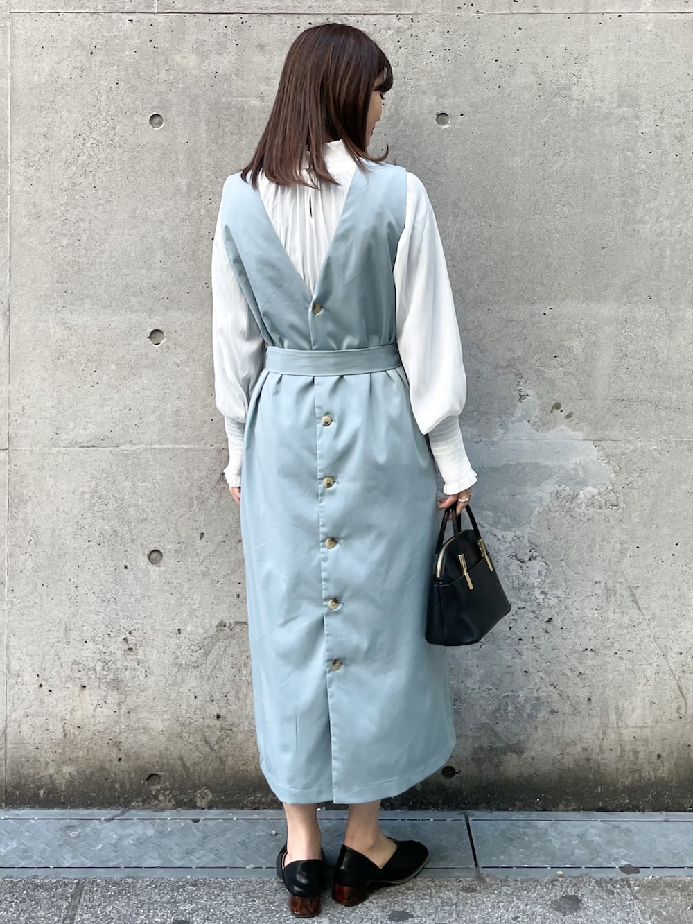 グリーン系のジャンパースカート、ブラック系のショルダーバッグ、ブラック系のその他シューズを着用したレディースの春コーディネートの2枚目の写真