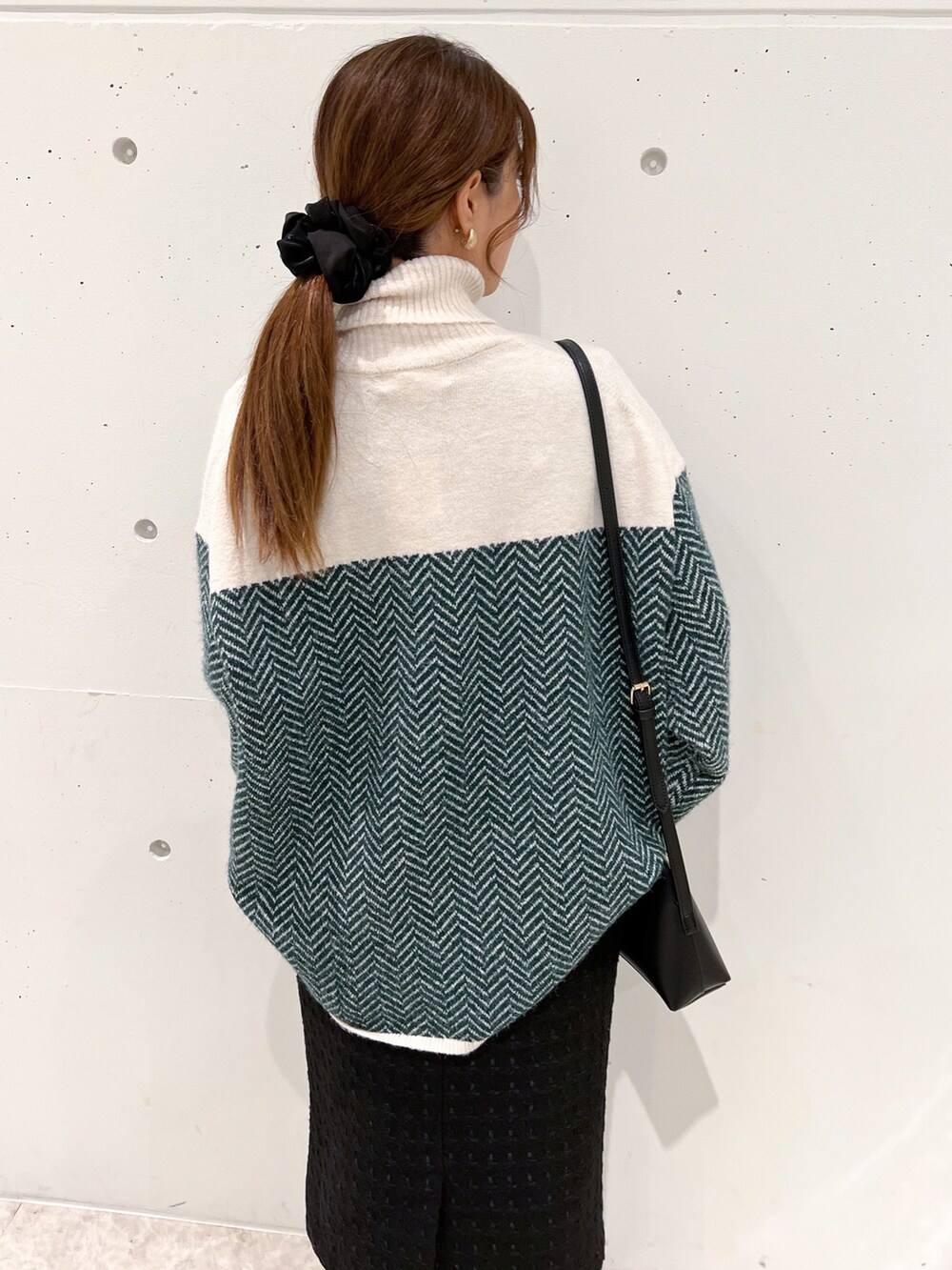 グリーン系のニット/セーター、ブラック系のスカート、ブラック系のショルダーバッグを着用したレディースの秋コーディネートの5枚目の写真