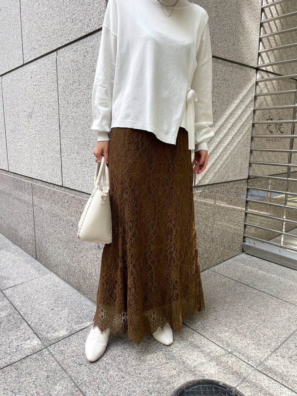 ホワイト系のニット/セーター、グリーン系のスカート、ホワイト系のショルダーバッグを着用したレディースの冬コーディネートの5枚目の写真