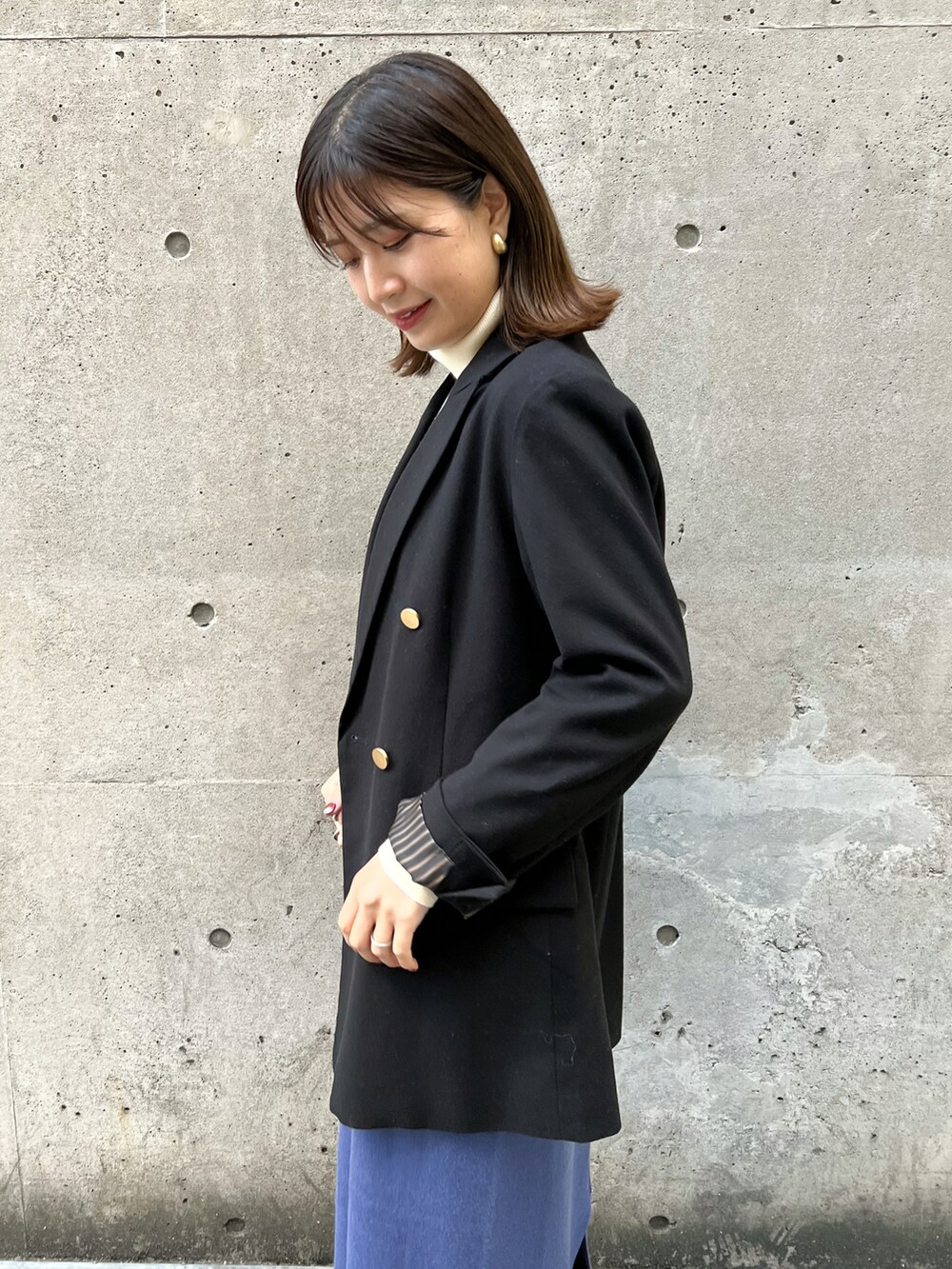 ブラック系のテーラードジャケット、ブルー系のジャンパースカート、ホワイト系のニット/セーターを着用したレディースの冬コーディネートの4枚目の写真