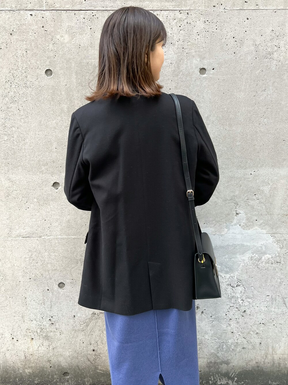 ブラック系のテーラードジャケット、ブルー系のジャンパースカート、ホワイト系のニット/セーターを着用したレディースの冬コーディネートの5枚目の写真